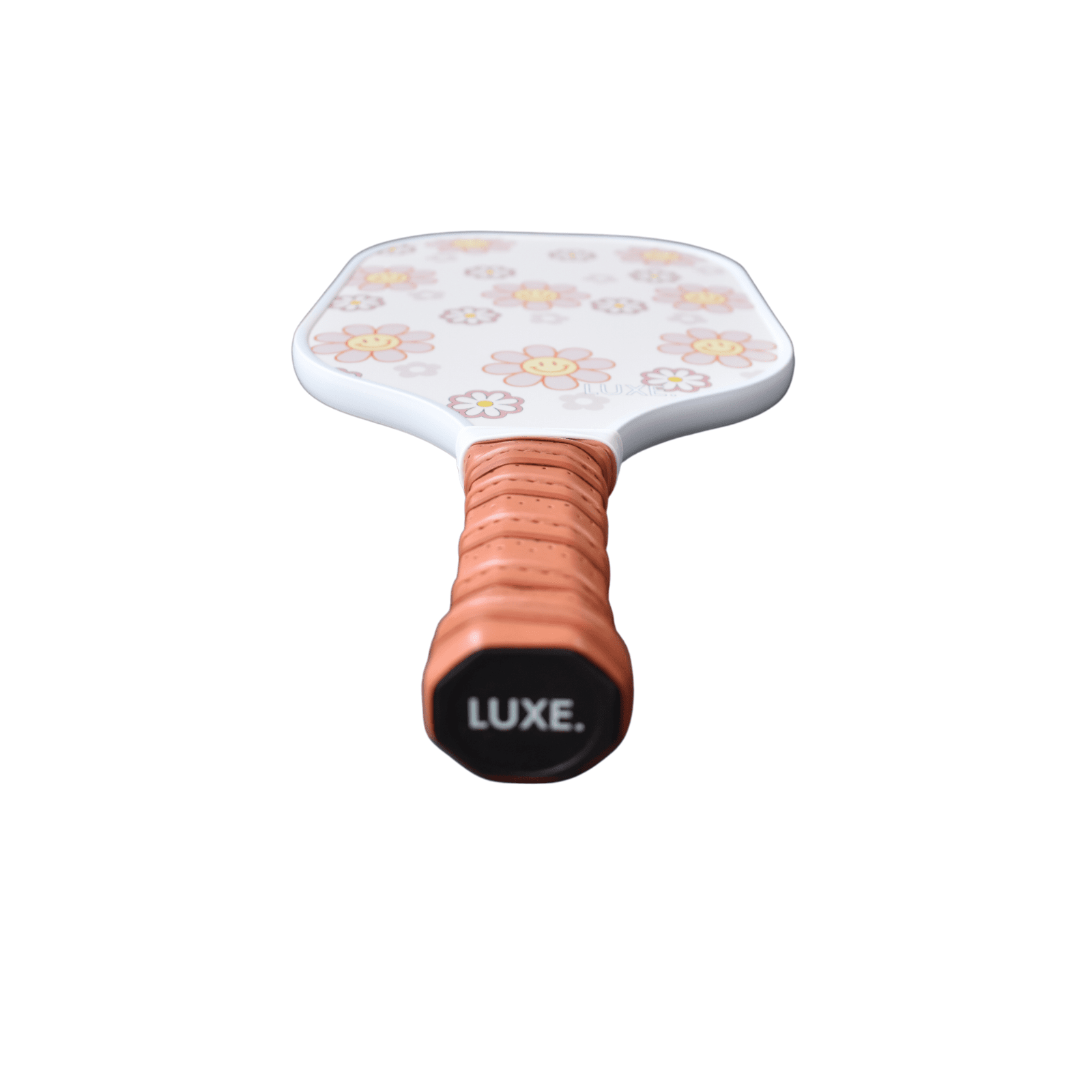 Close-up of a white pickleball paddle with a floral pattern, wrapped in an orange grip and labeled "LUXE."