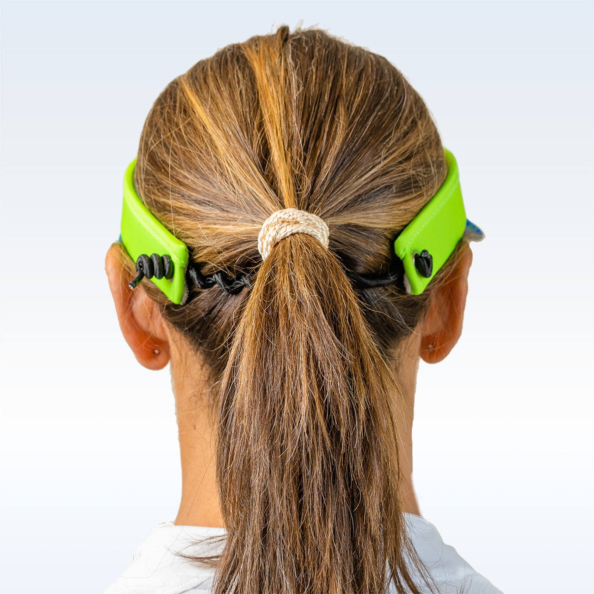 Bright green visor from Pickleball Bella, with black cords, on a woman's head with a ponytail, back view.