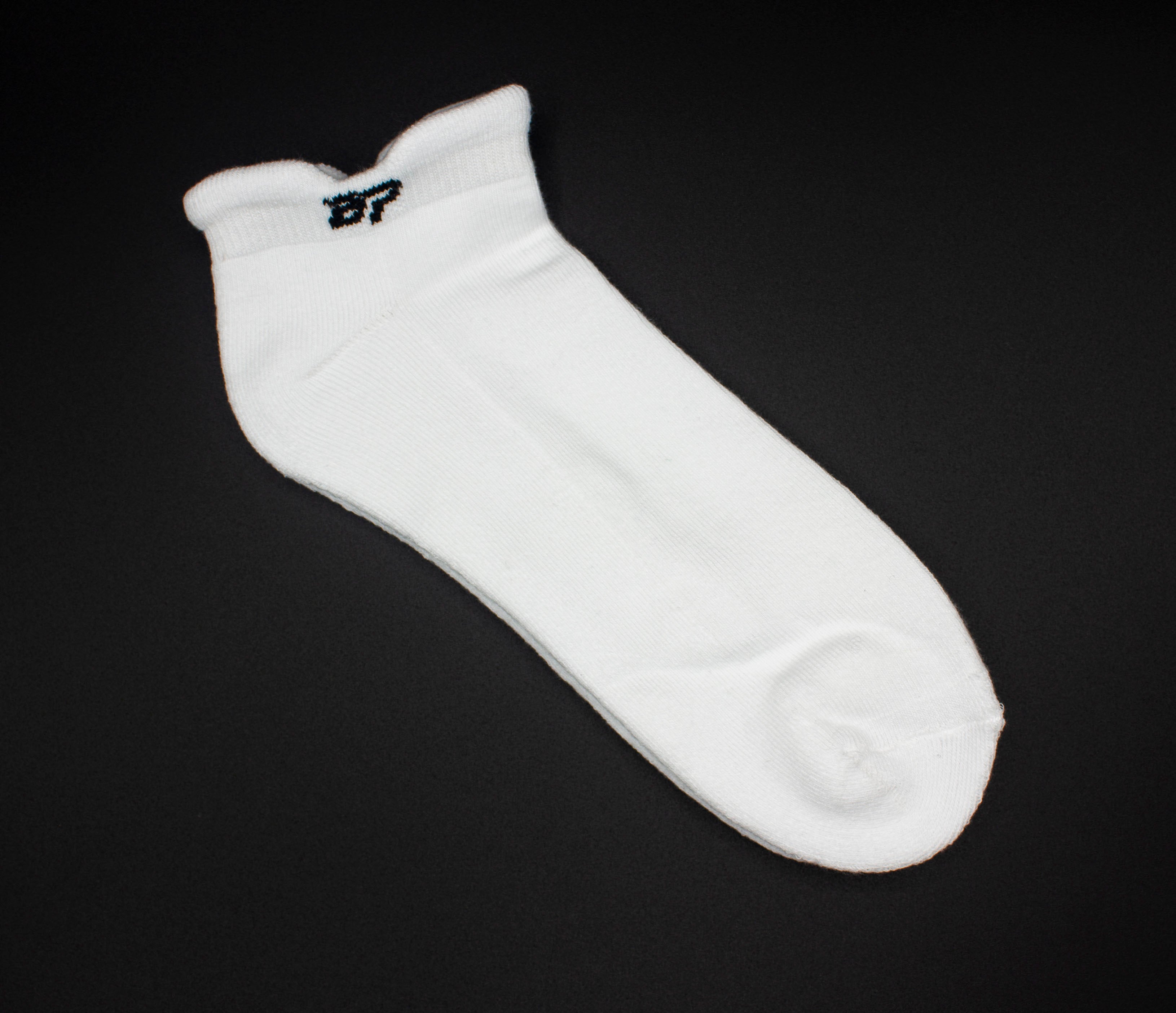 White ankle performance socks by Bodhi Performance, featuring a small black BP logo on the cuff, lying diagonally.