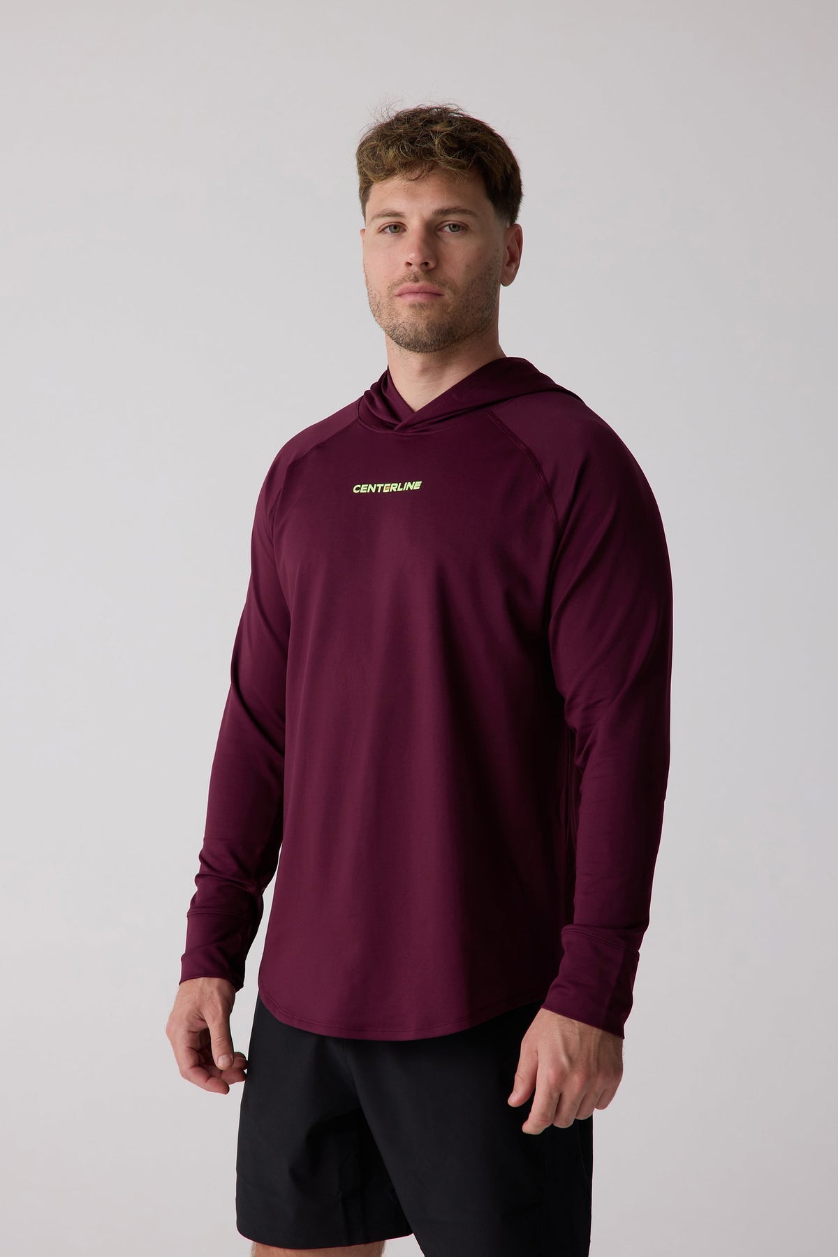 Burgundy men's layering hoodie by Centerline with small chest logo, long sleeves, and hood, shown on model in front view.