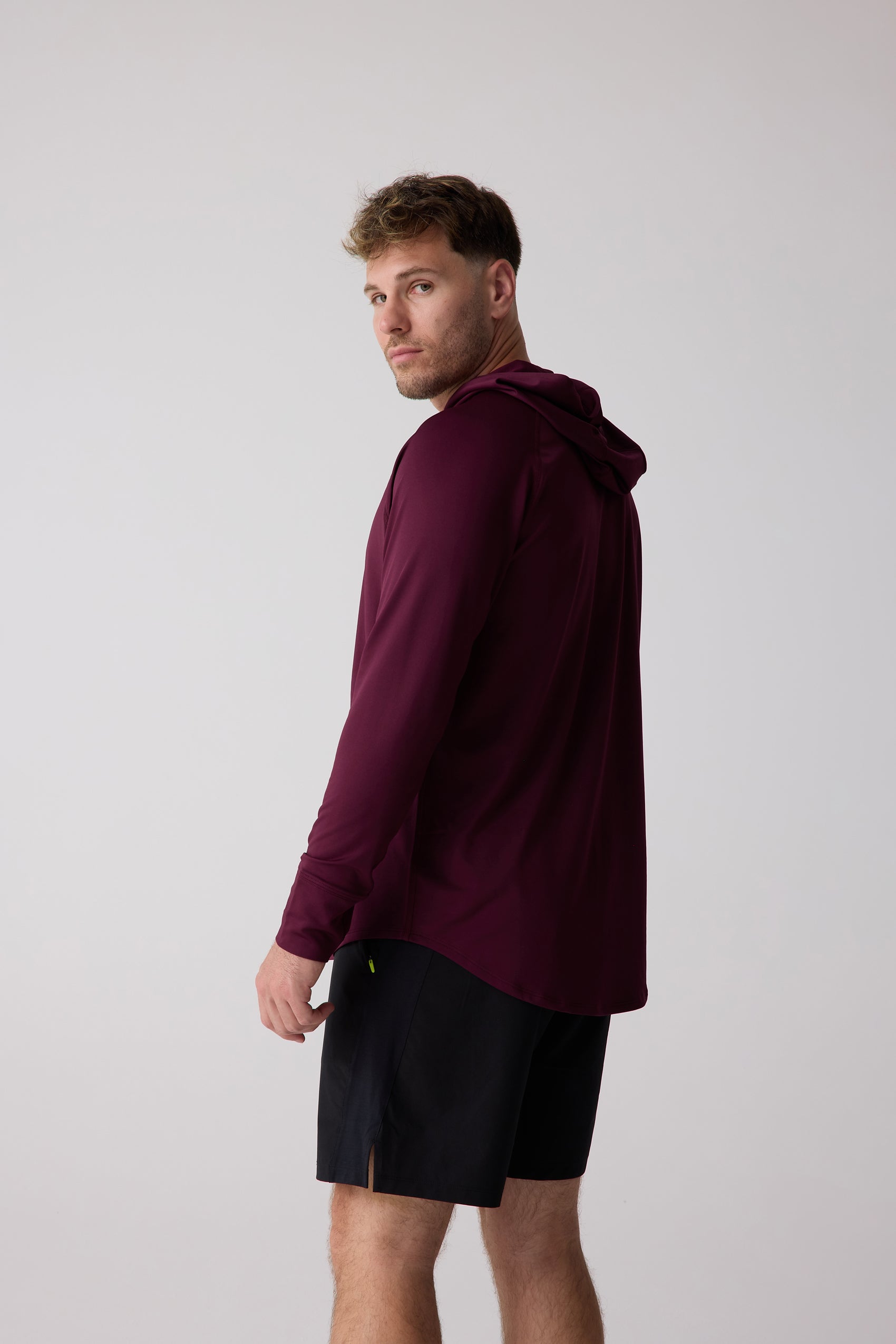 Maroon Men's Layering Hoodie by Centerline Athletics, worn by a man looking over his shoulder with black shorts.