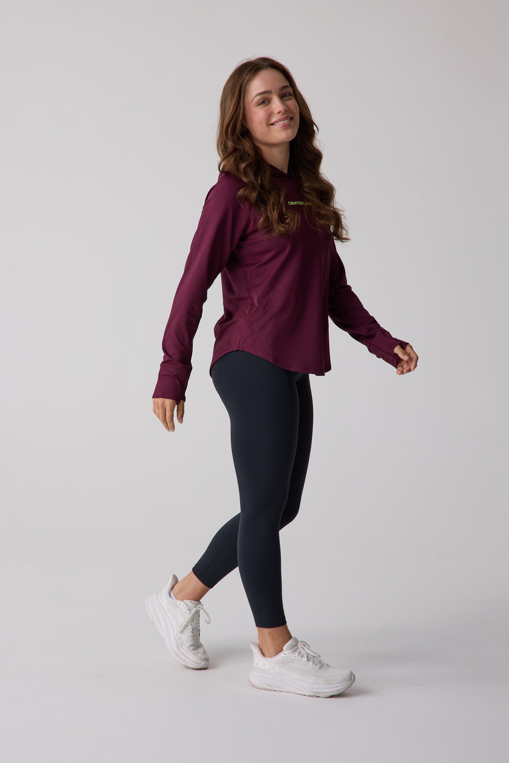 Maroon Women's Layering Hoodie by Centerline Athletics, with thumbholes and subtle chest logo, styled with black leggings.