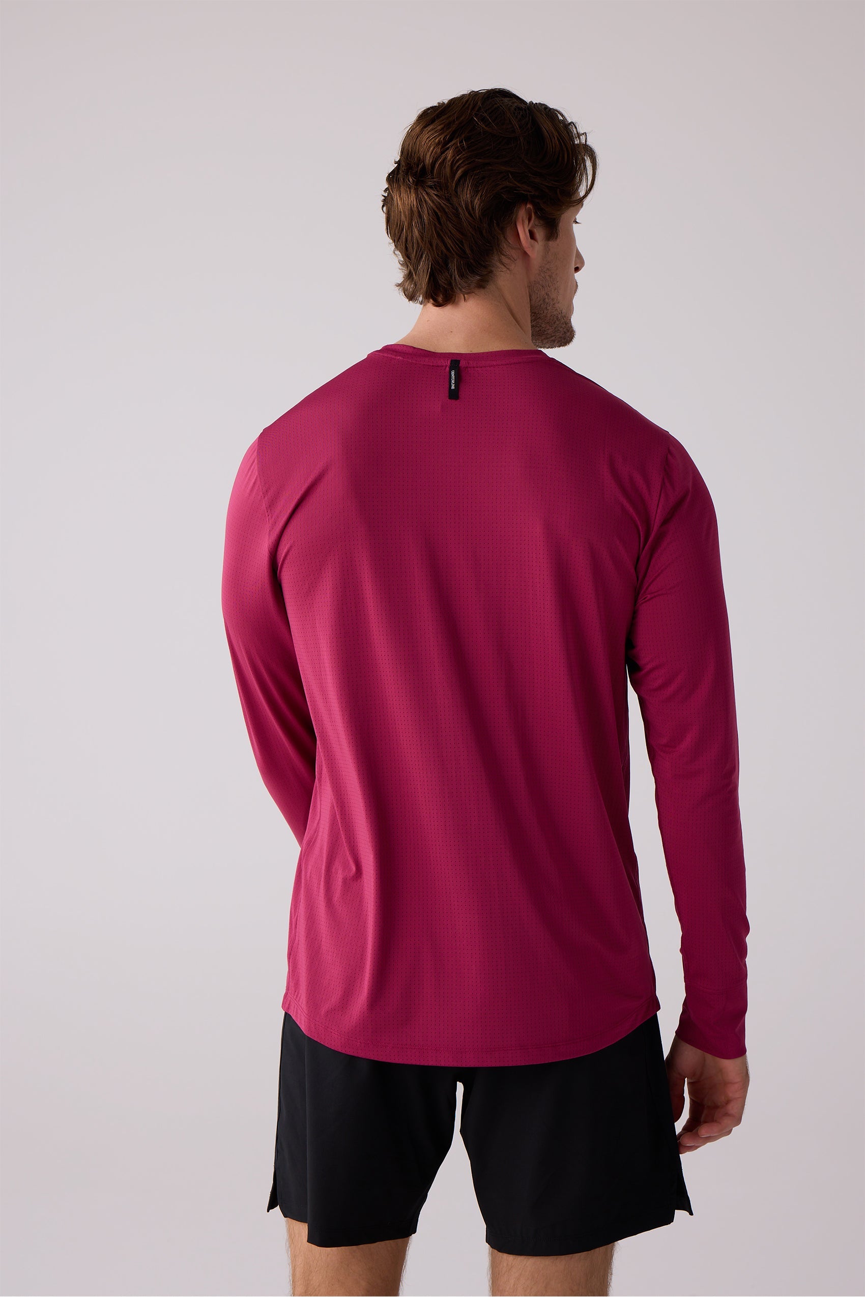 Deep pink men's AirLite long-sleeve shirt by Centerline Athletics, with a perforated texture and small black brand tag, shown from the back.
