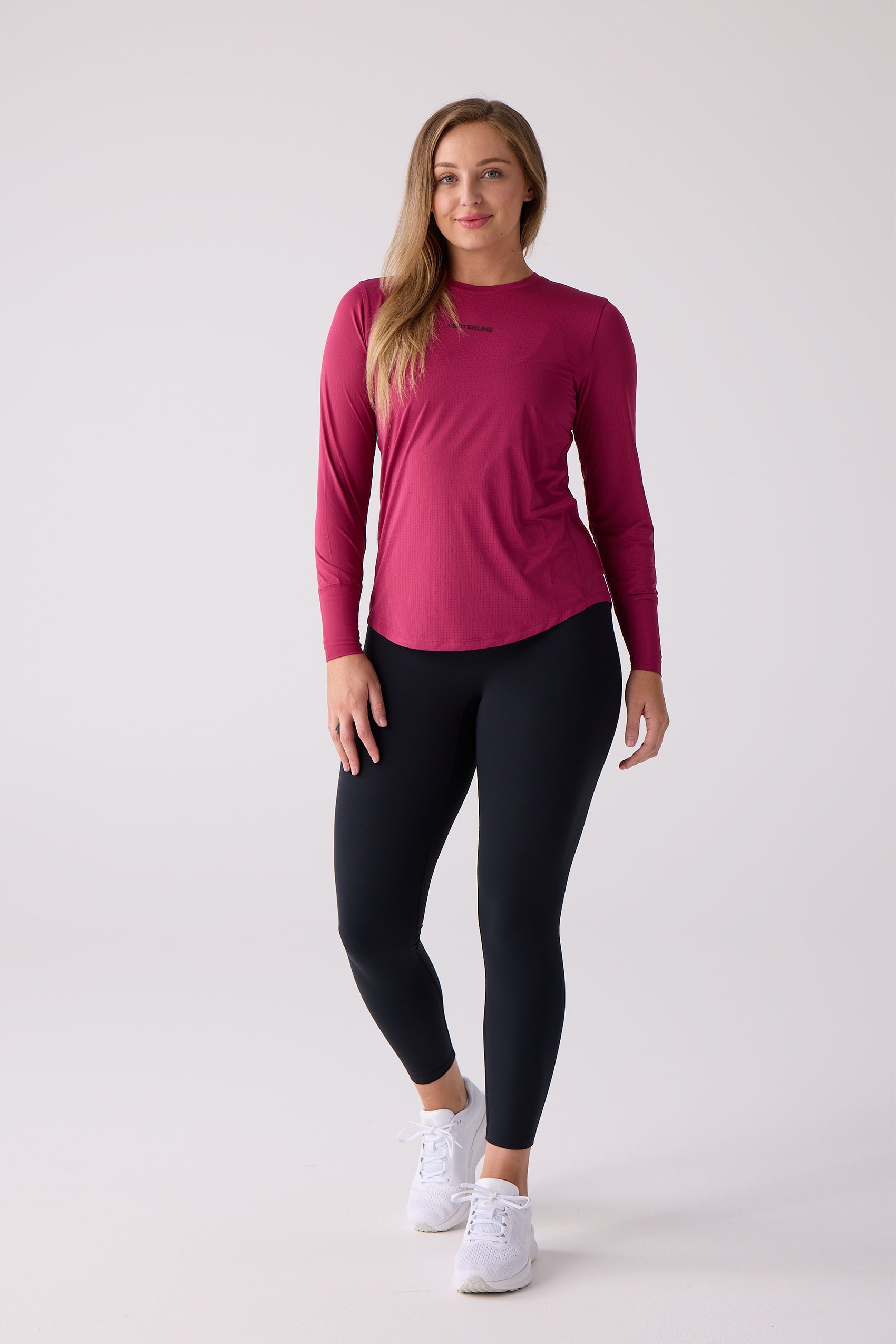 Women's magenta AirLite long sleeve shirt by Centerline Athletics, with subtle dotted texture and rounded hem, worn with black leggings.