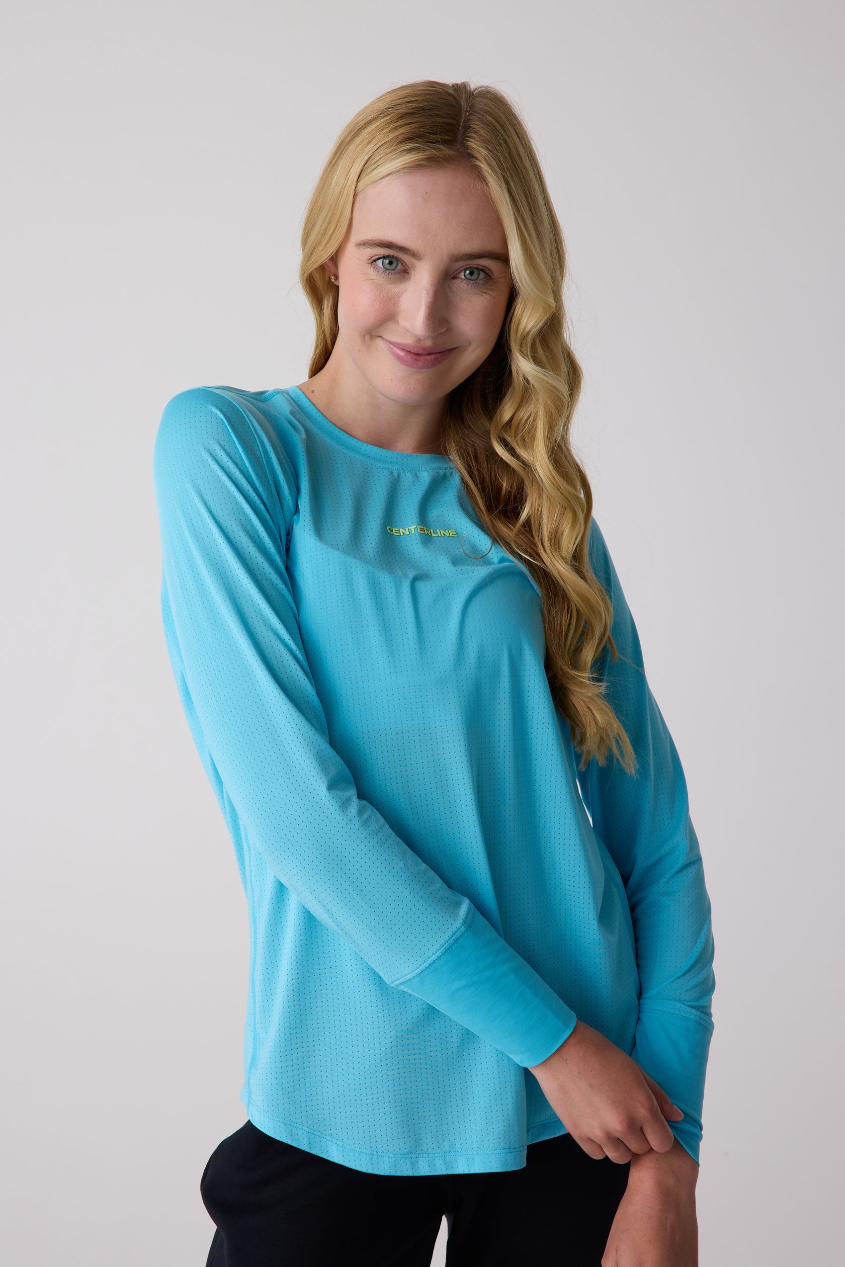 Turquoise Women's AirLite Long Sleeve by Centerline Athletics, featuring perforated fabric and a yellow-green chest logo.