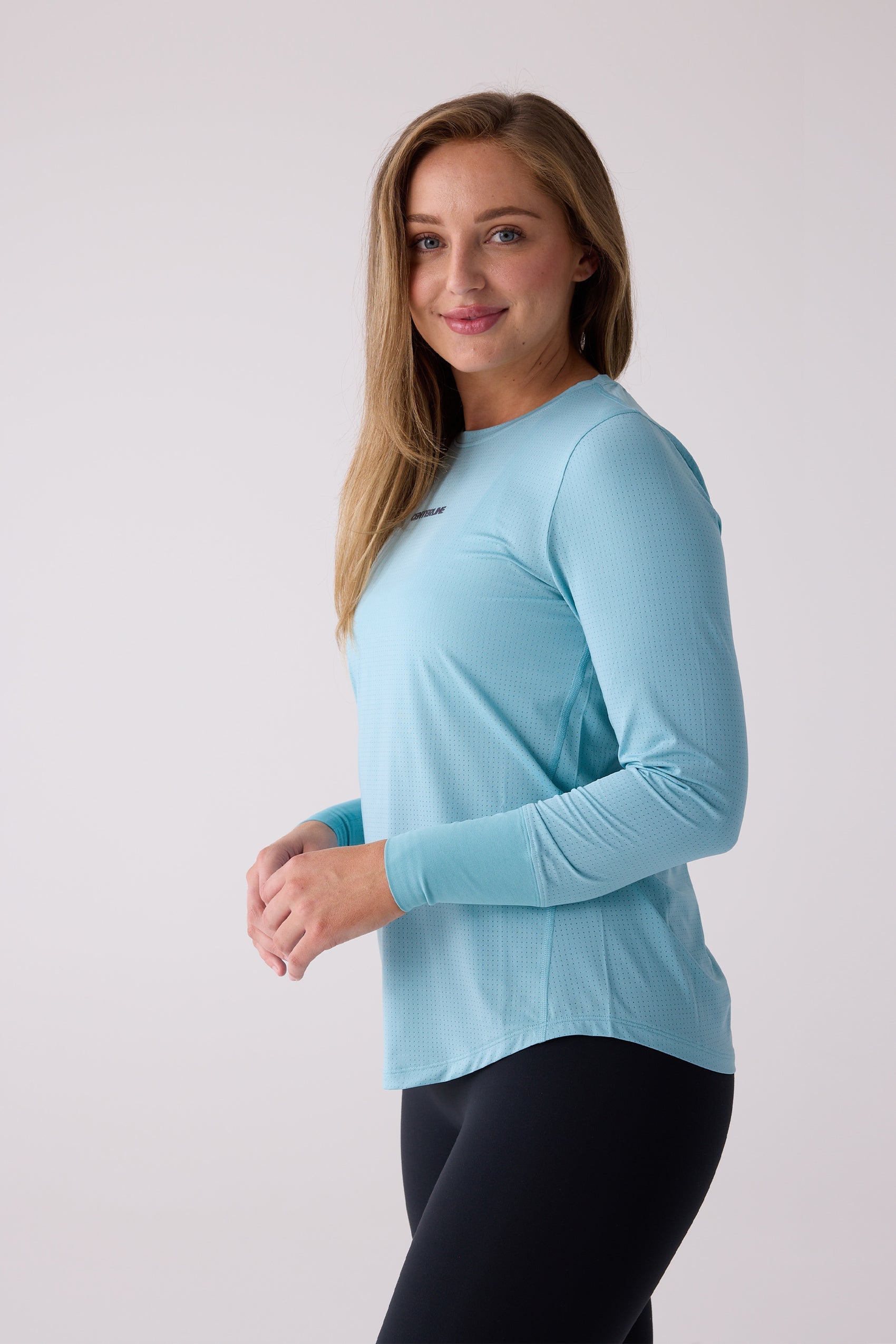 Light blue Women's AirLite long sleeve shirt by Centerline Athletics, featuring perforated texture and chest logo, worn with black leggings.