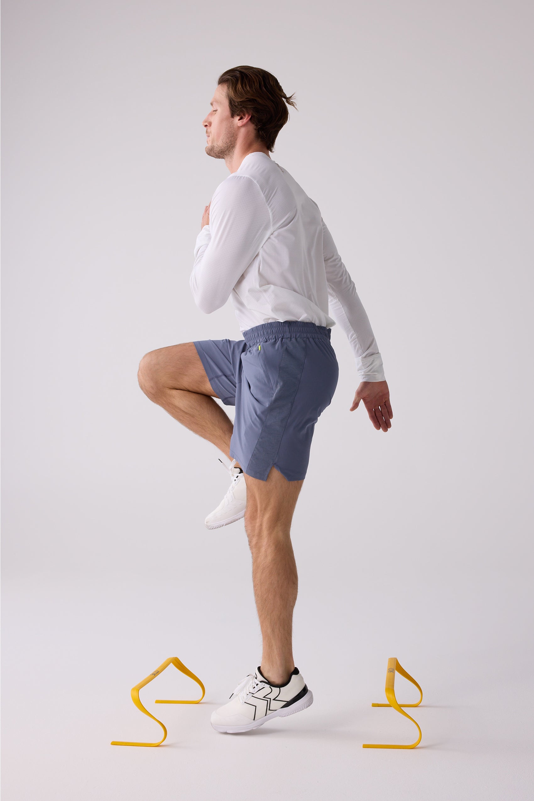 Blue-grey AirLite 7" unlined men's shorts by Centerline Athletics, with elastic waist, side panels, and neon yellow accent, worn by a man.