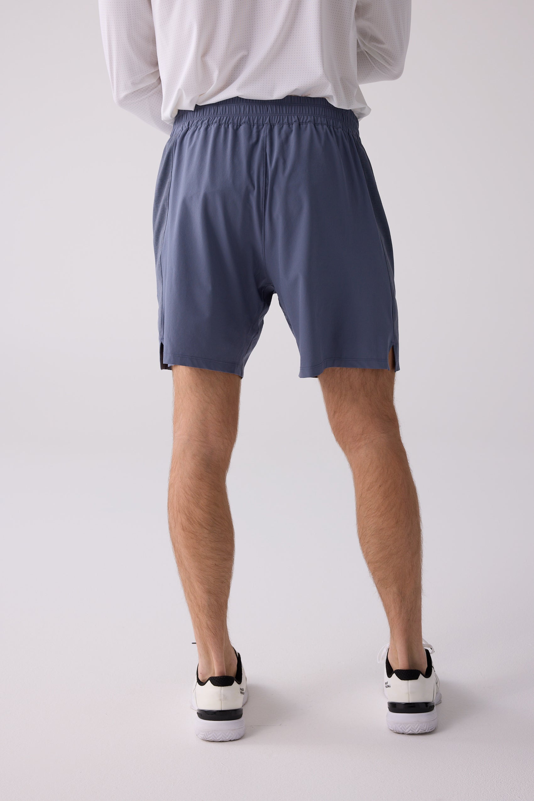Blue men's shorts by Centerline Athletics with elastic waistband and side split hems, worn from the back with a white long-sleeve shirt and sneakers.