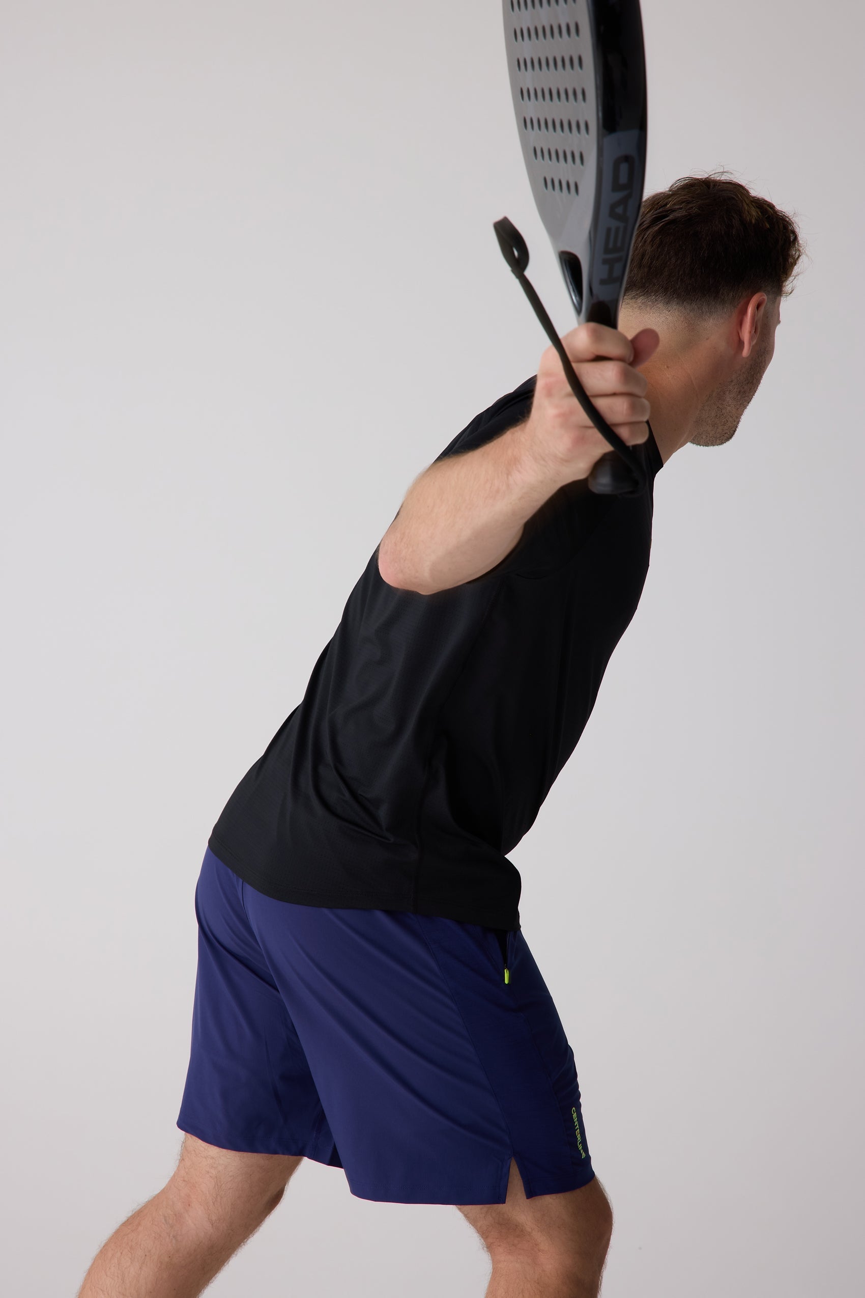 Navy blue AirLite 7-inch unlined shorts from Centerline Athletics, with lime green zipper and side 'CENTERLINE' text, worn by a man in a black t-shirt.