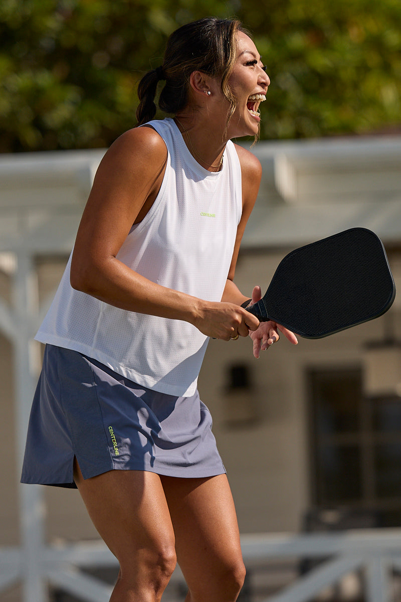 Grey AirLite skort by Centerline Athletics, with vertical brand text, worn by a woman playing pickleball.