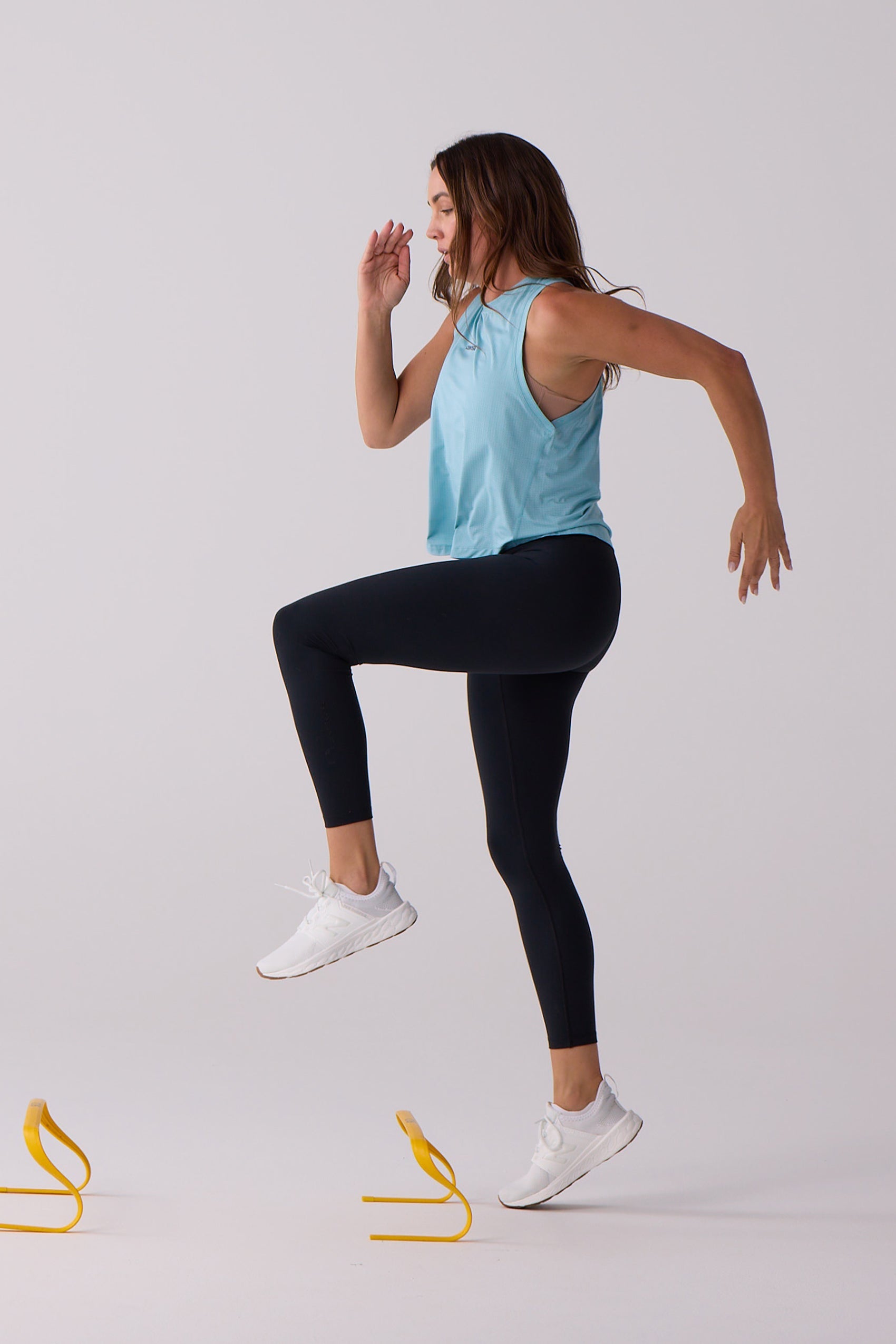 Light blue Women's AirLite Tank by Centerline Athletics, cropped and worn by a model exercising in black leggings.