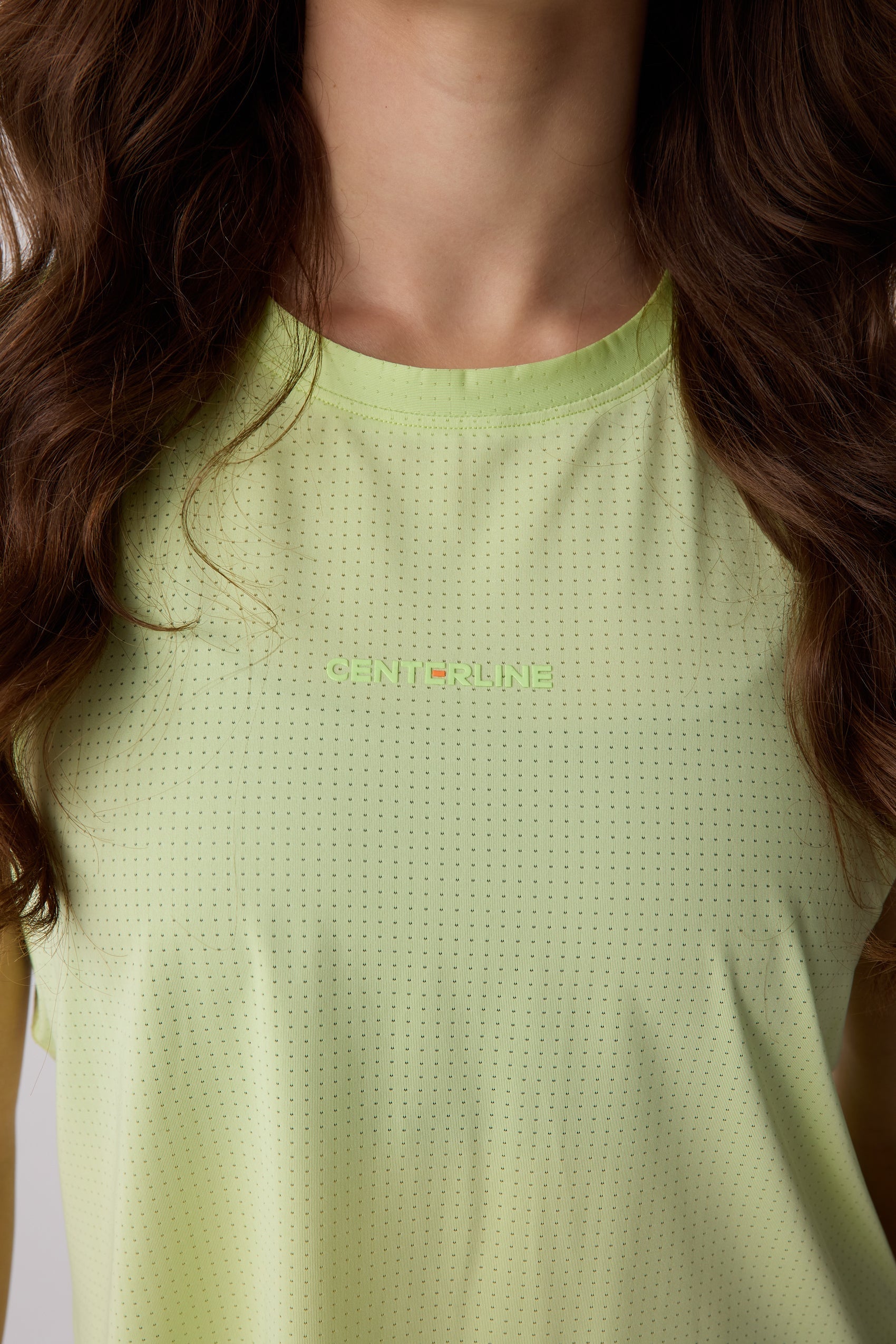 Light green perforated women's tank top by Centerline Athletics, featuring a CENTERLINE logo and all-over dot pattern.