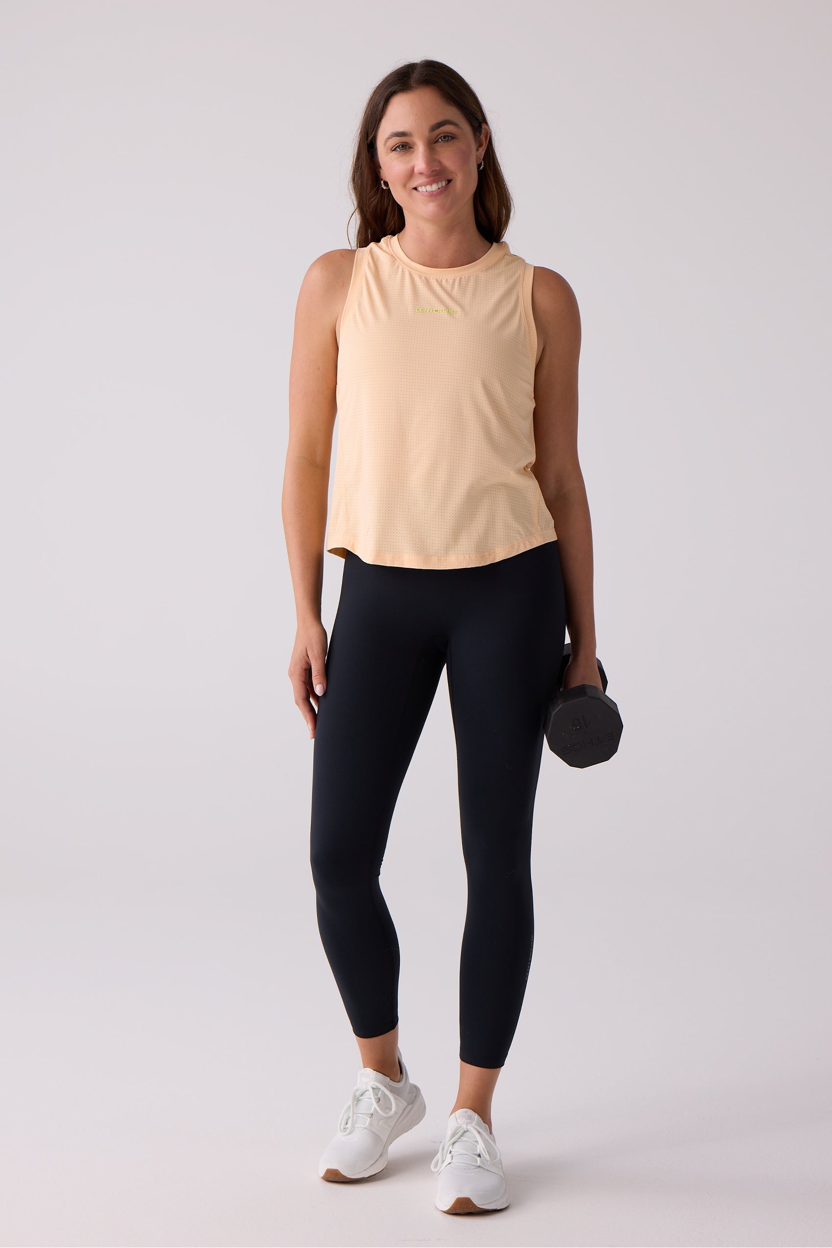 Light peach perforated women's tank by Centerline Athletics, featuring a chest logo, worn with black leggings.