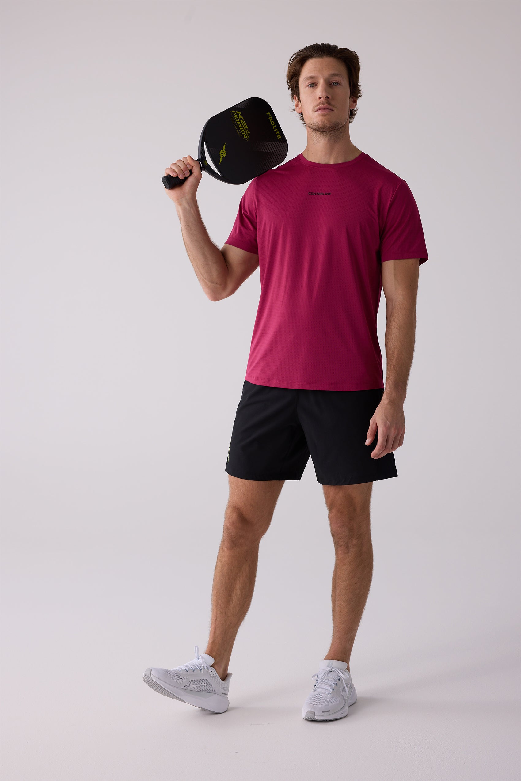 Magenta Men's AirLite Tee by Centerline Athletics, featuring a subtle textured pattern, worn by a man with black shorts and white sneakers.