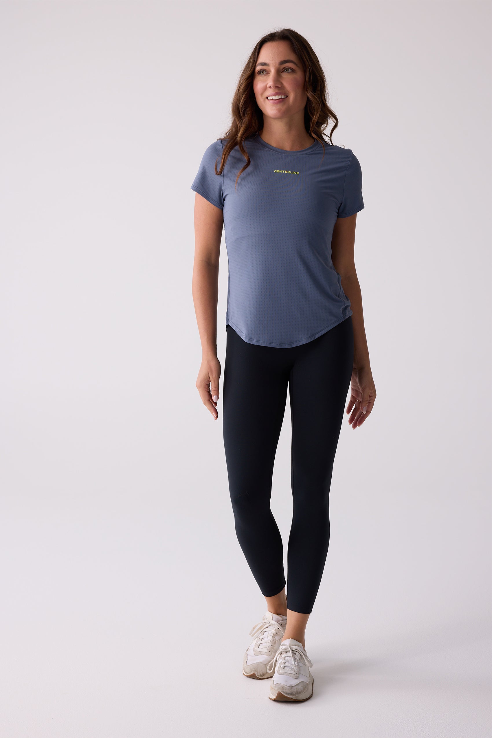 Blue short sleeve Women's AirLite tee by Centerline Athletics, with subtle textured fabric and yellow 'CENTERLINE' text, worn with black leggings and white sneakers.