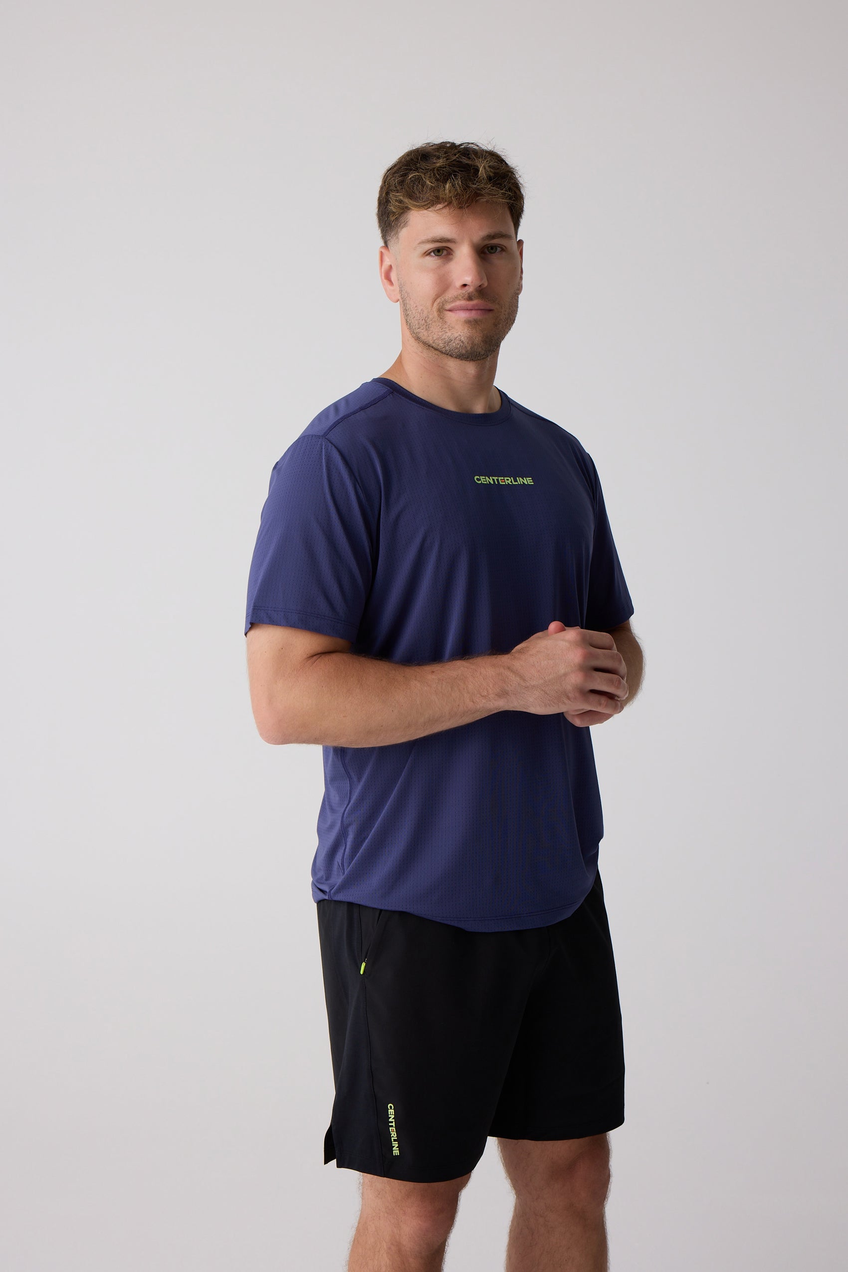 Blue men's t-shirt by Centerline Athletics, featuring a mesh texture and lime green branding, worn with black shorts.