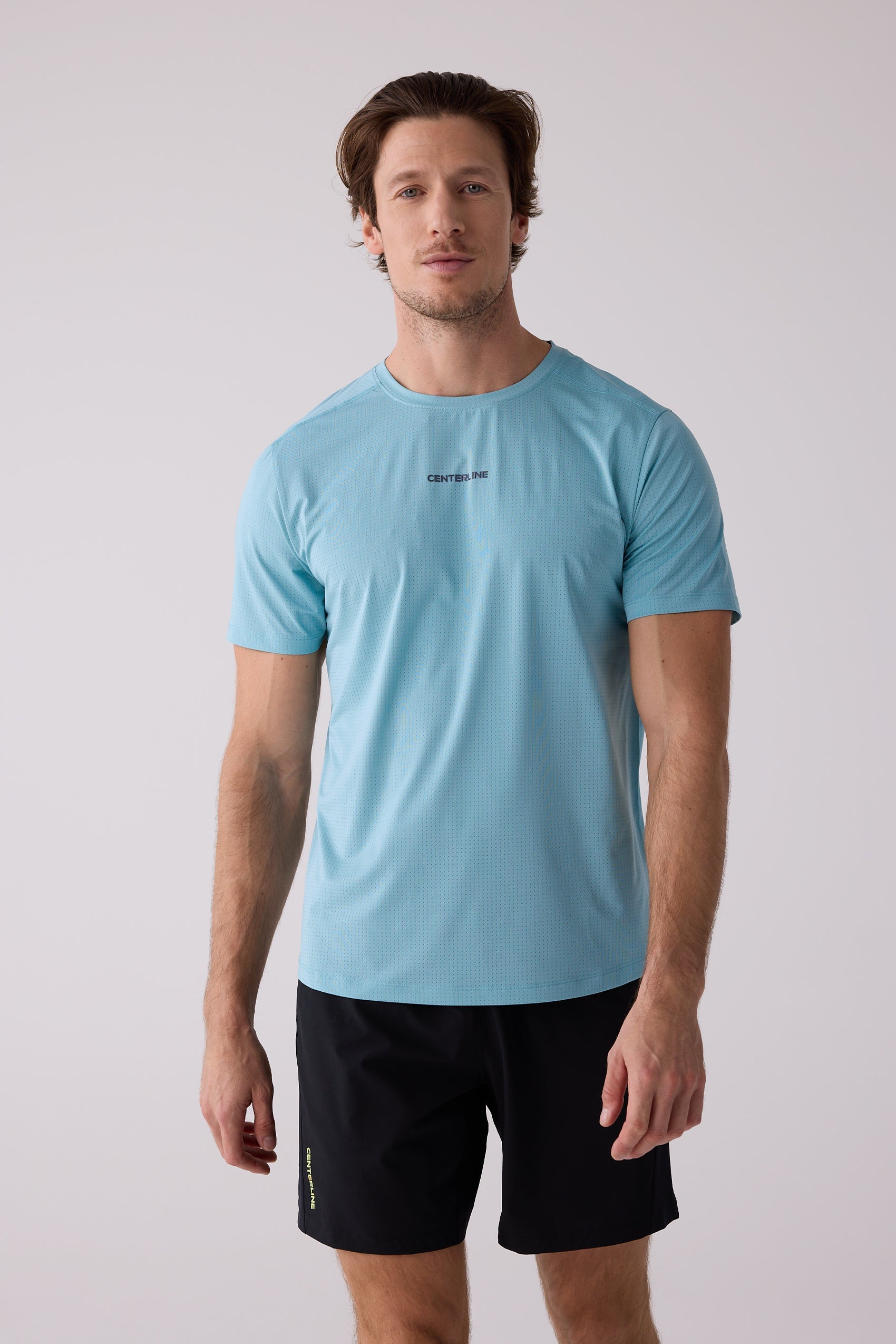 Men's light blue perforated short-sleeve tee by Centerline Athletics, with a chest logo, worn with black shorts.
