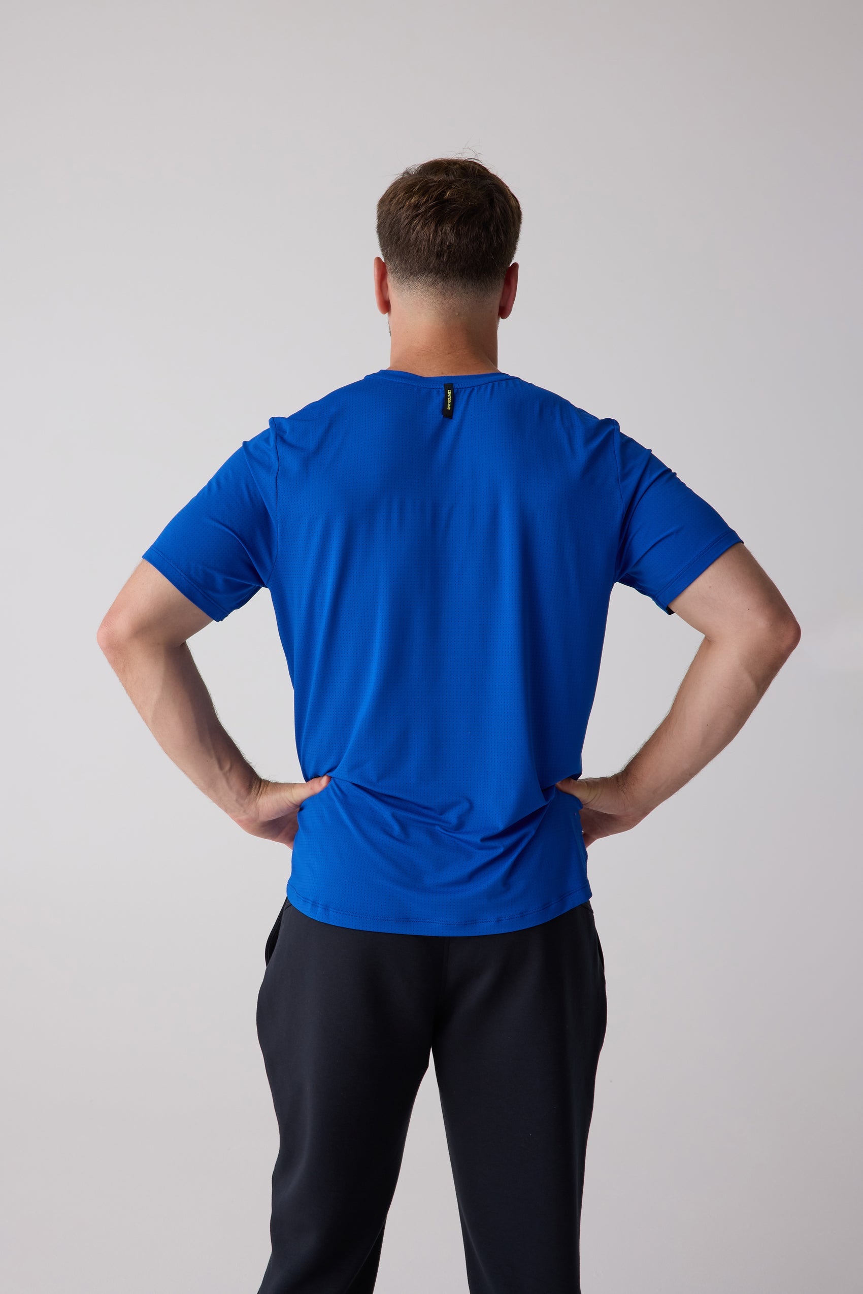 Blue short-sleeved men's AirLite tee by Centerline Athletics, back view with textured fabric and branded neck tag.