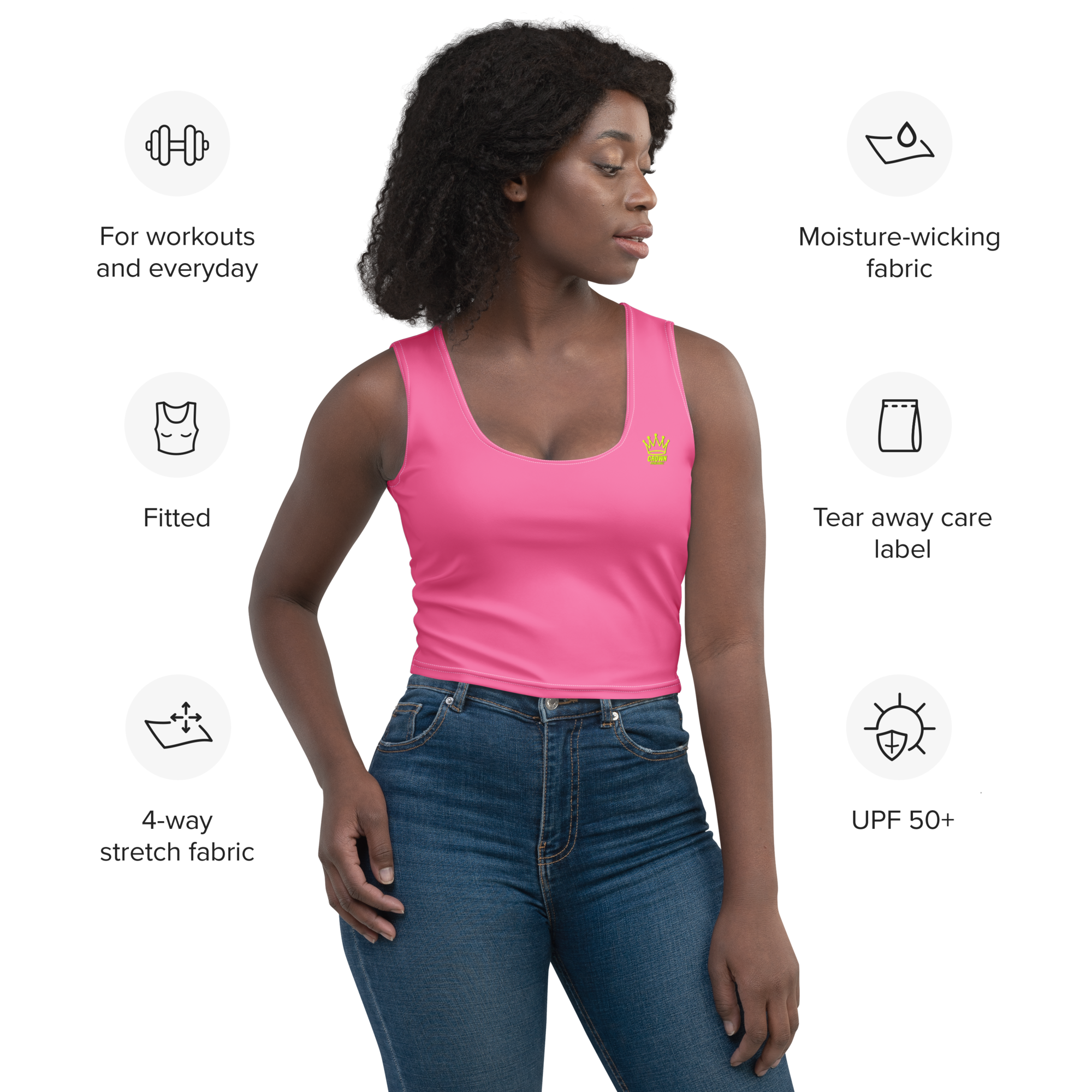 A woman wearing a pink crop top with a crown logo and blue jeans.