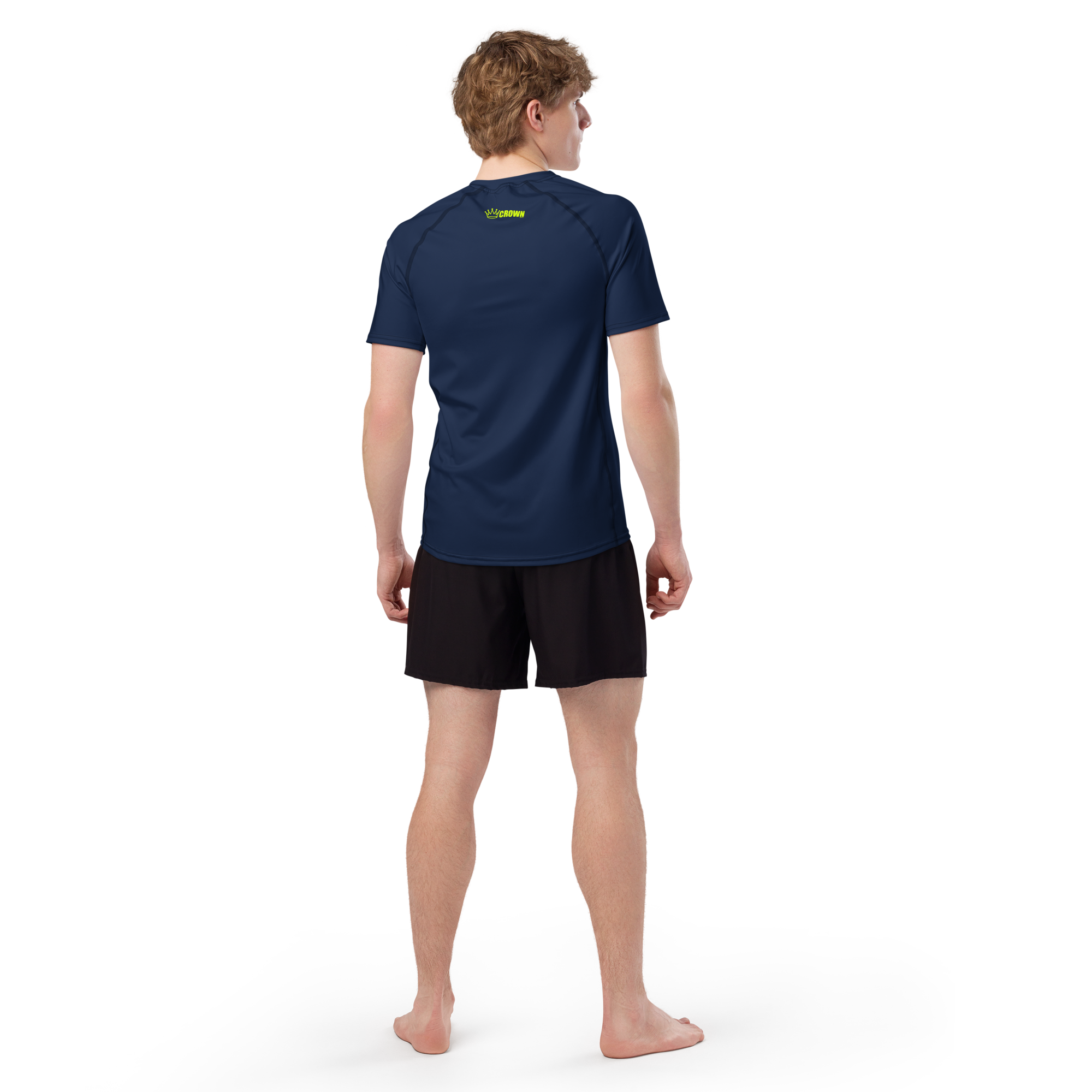 Man facing away, wearing a blue T-shirt with "Crown" in green, black shorts, and barefoot on black background.