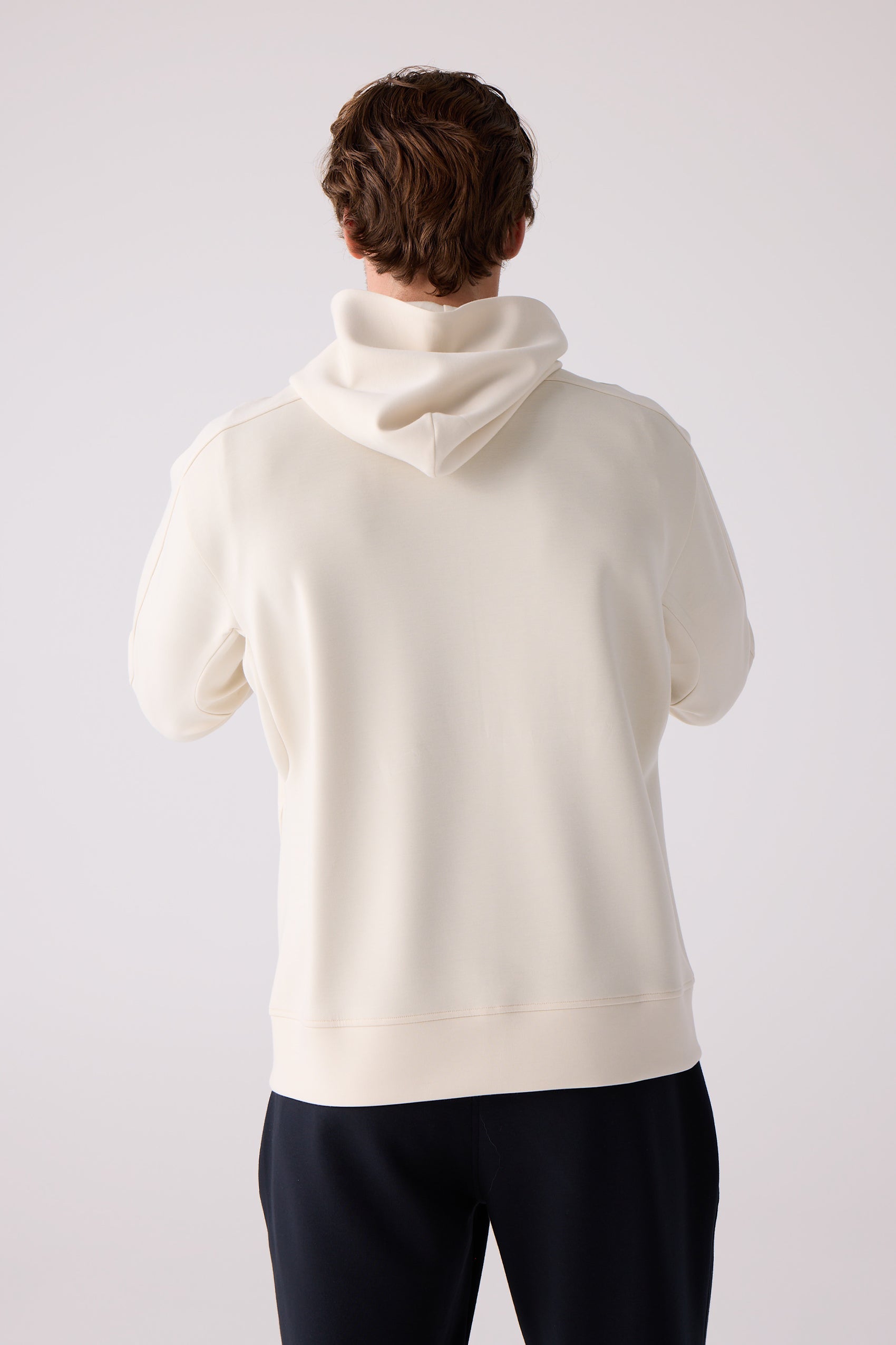 Cream unisex hooded sweatshirt by Centerline Athletics, back view on a man, with dark pants.