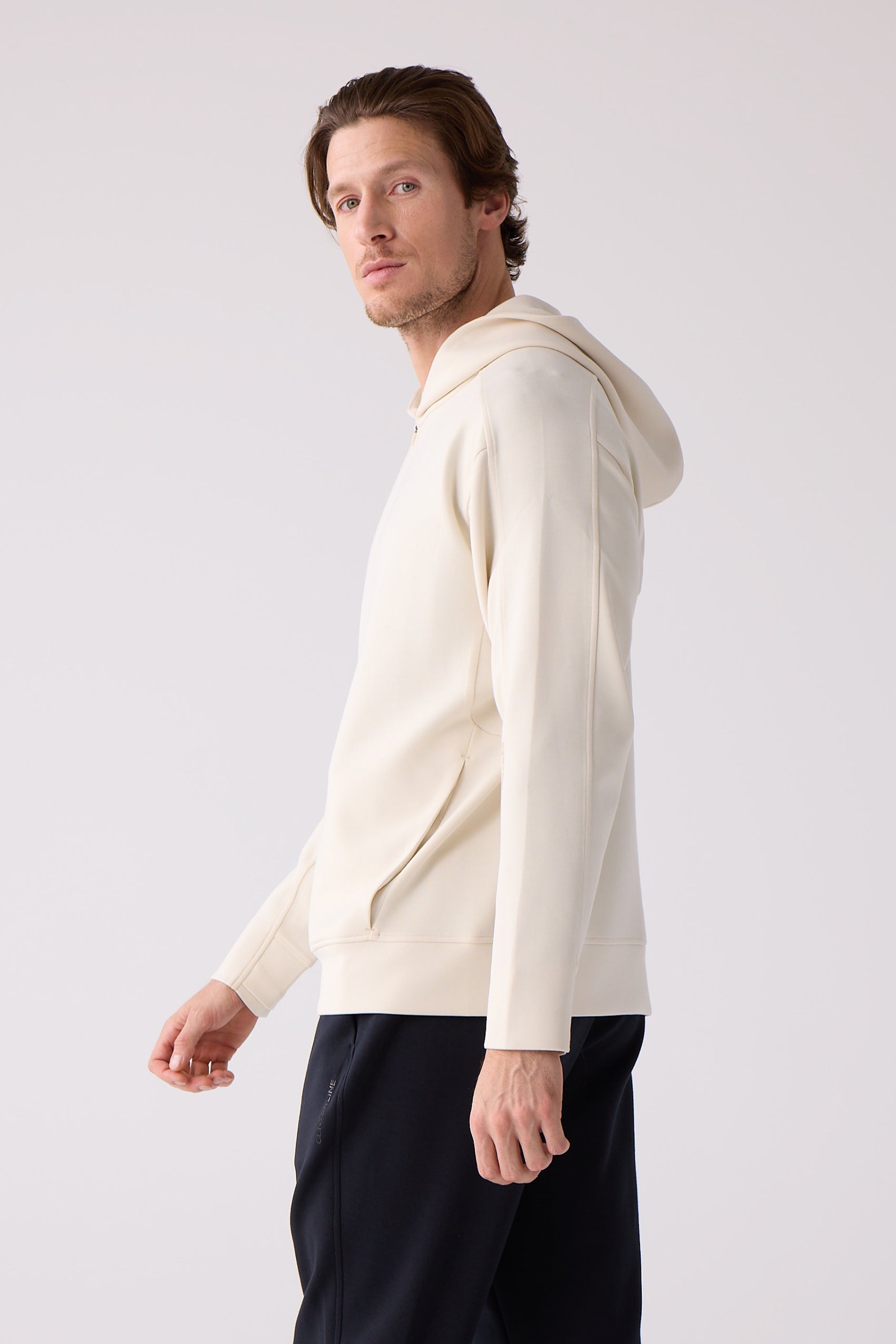 Cream Unisex Crew Sweatshirt by Centerline Athletics, worn by a man in dark pants, shown from the side.