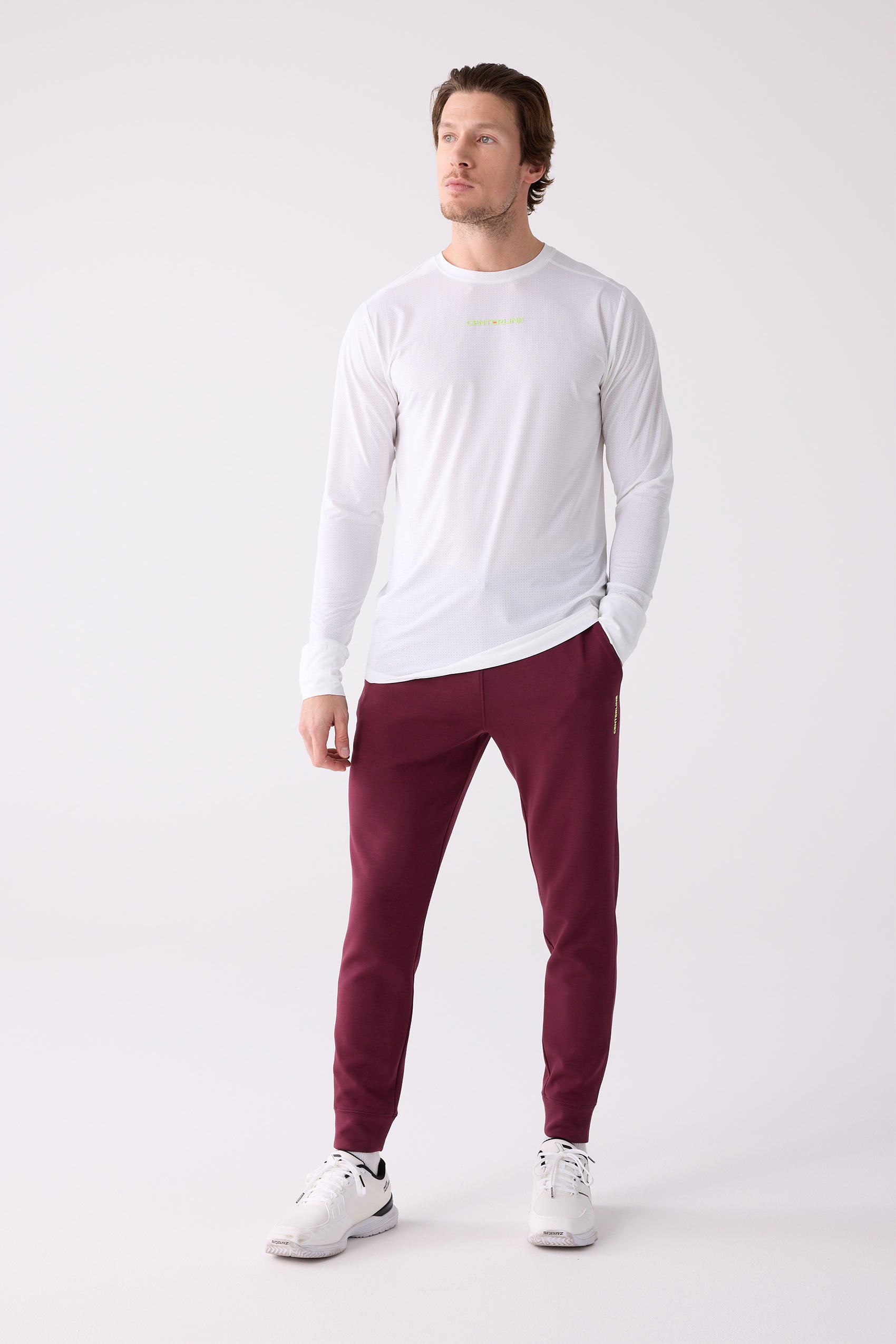 Burgundy Men's Après Jogger by Centerline Athletics with subtle branding on the leg, paired with a white long-sleeve top and sneakers.