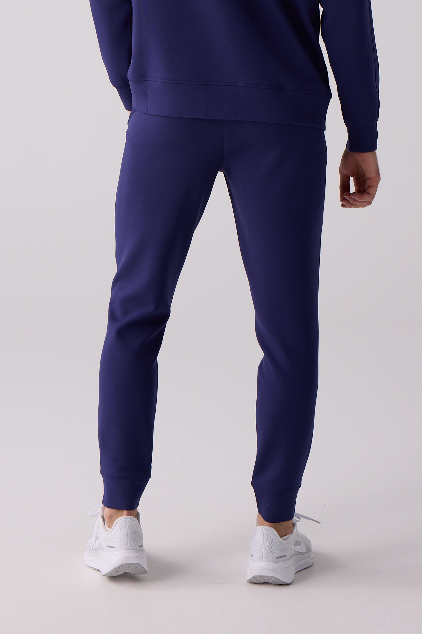 Dark blue Men's Après Jogger by Centerline Athletics, featuring ribbed cuffs, paired with white sneakers, back view.