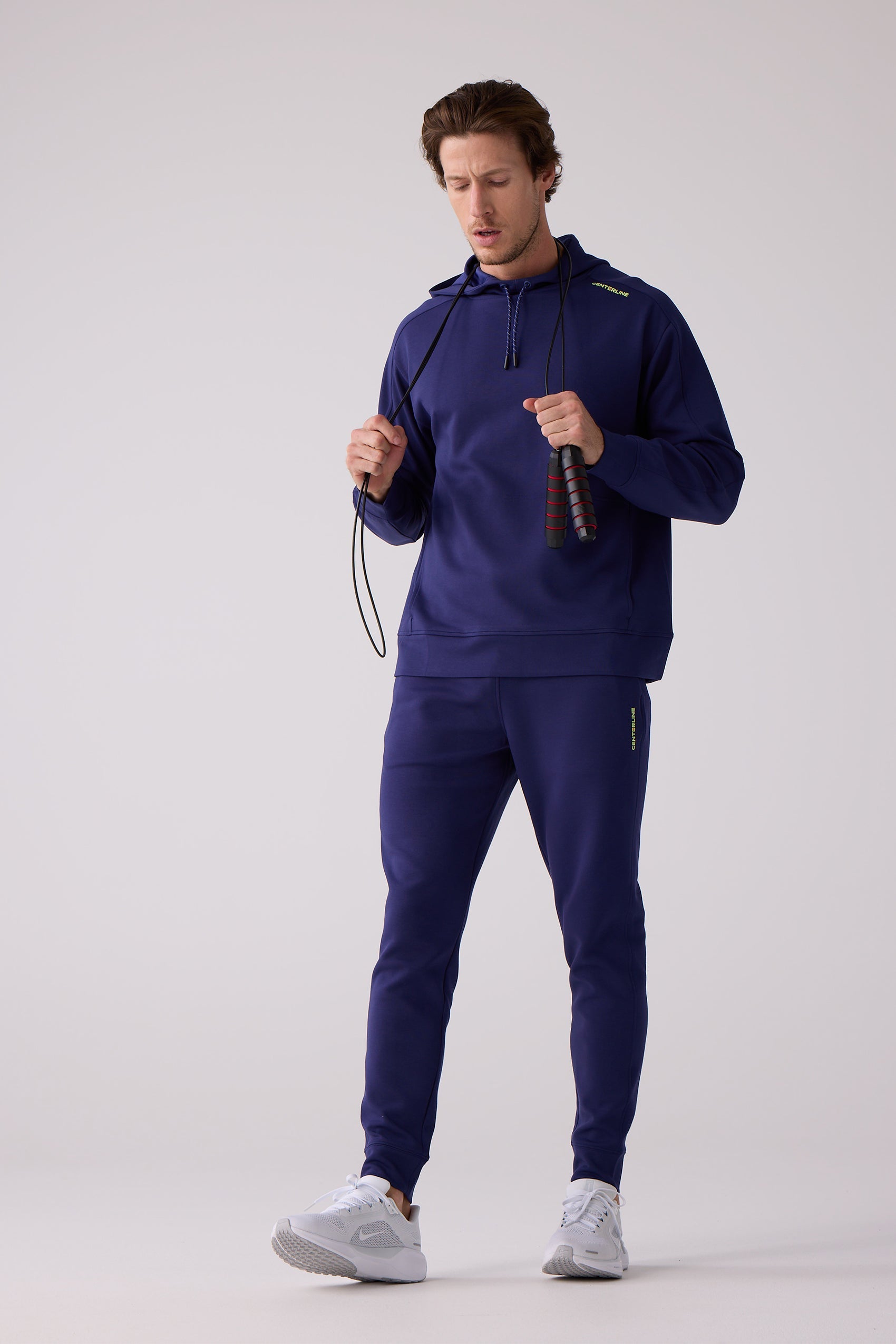 Navy blue jogger pants by Centerline Athletics, featuring a subtle yellow logo, paired with a matching hoodie and white sneakers.