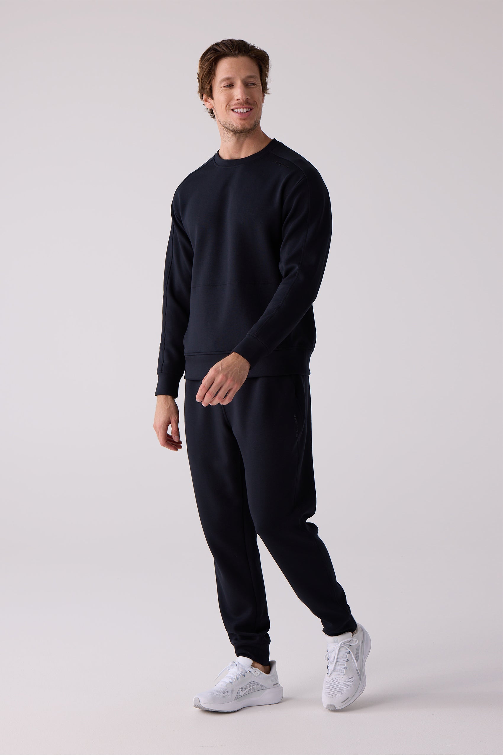 Navy blue men's crew sweatshirt by Centerline Athletics with subtle shoulder stitching, worn by a man with matching sweatpants and white athletic shoes.
