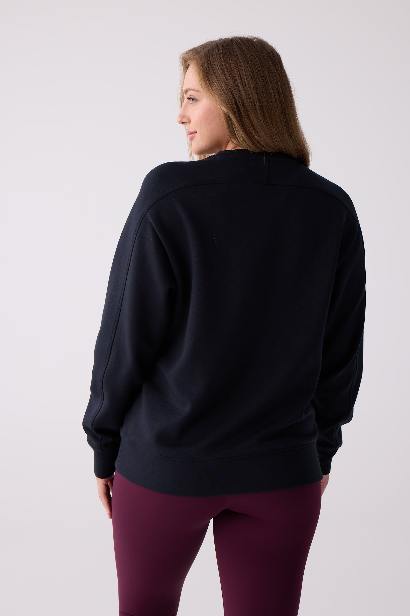 Women's navy long sleeve crew sweatshirt by Centerline Athletics, styled with burgundy leggings, shown from the back.