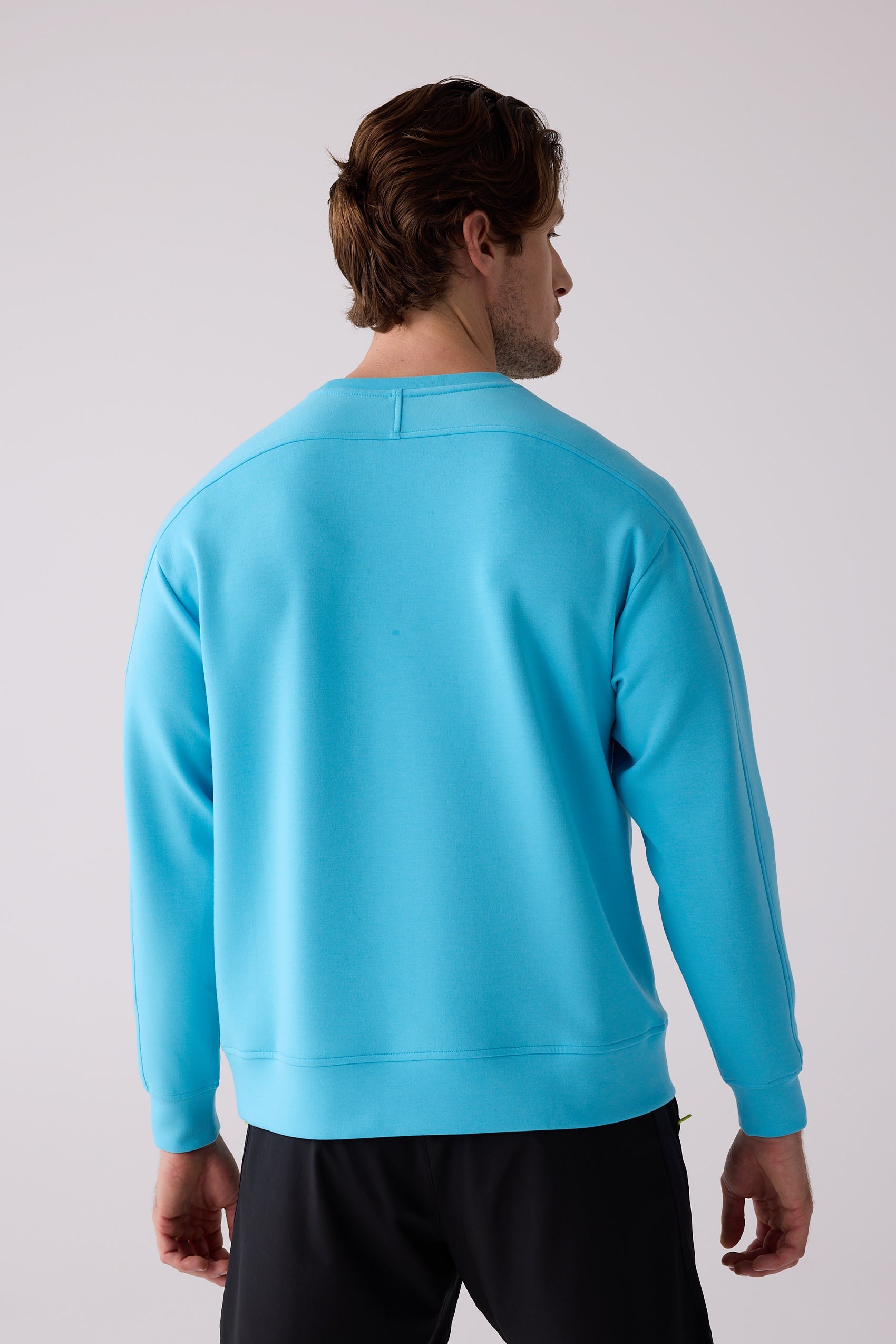 Blue long sleeve men's crew sweatshirt by Centerline Athletics, with smooth fabric and ribbed details, seen from the back.