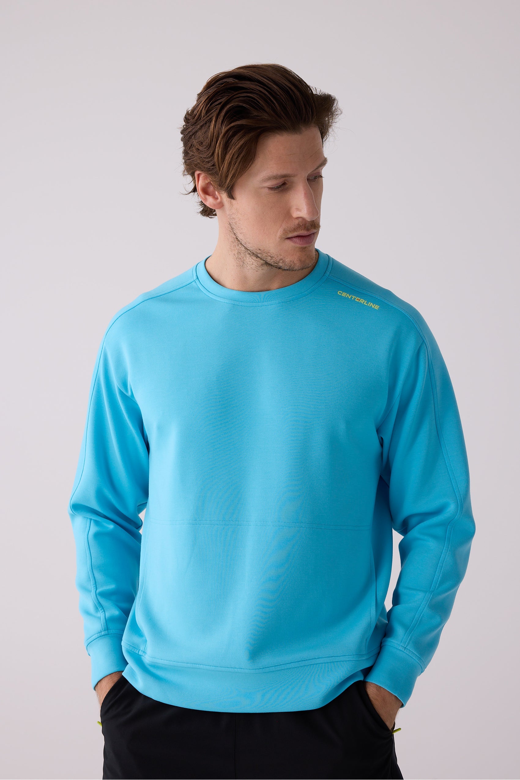 Aqua blue men's crew sweatshirt by Centerline Athletics, featuring yellow "CENTERLINE" on the shoulder, worn by a model with hands in pockets.