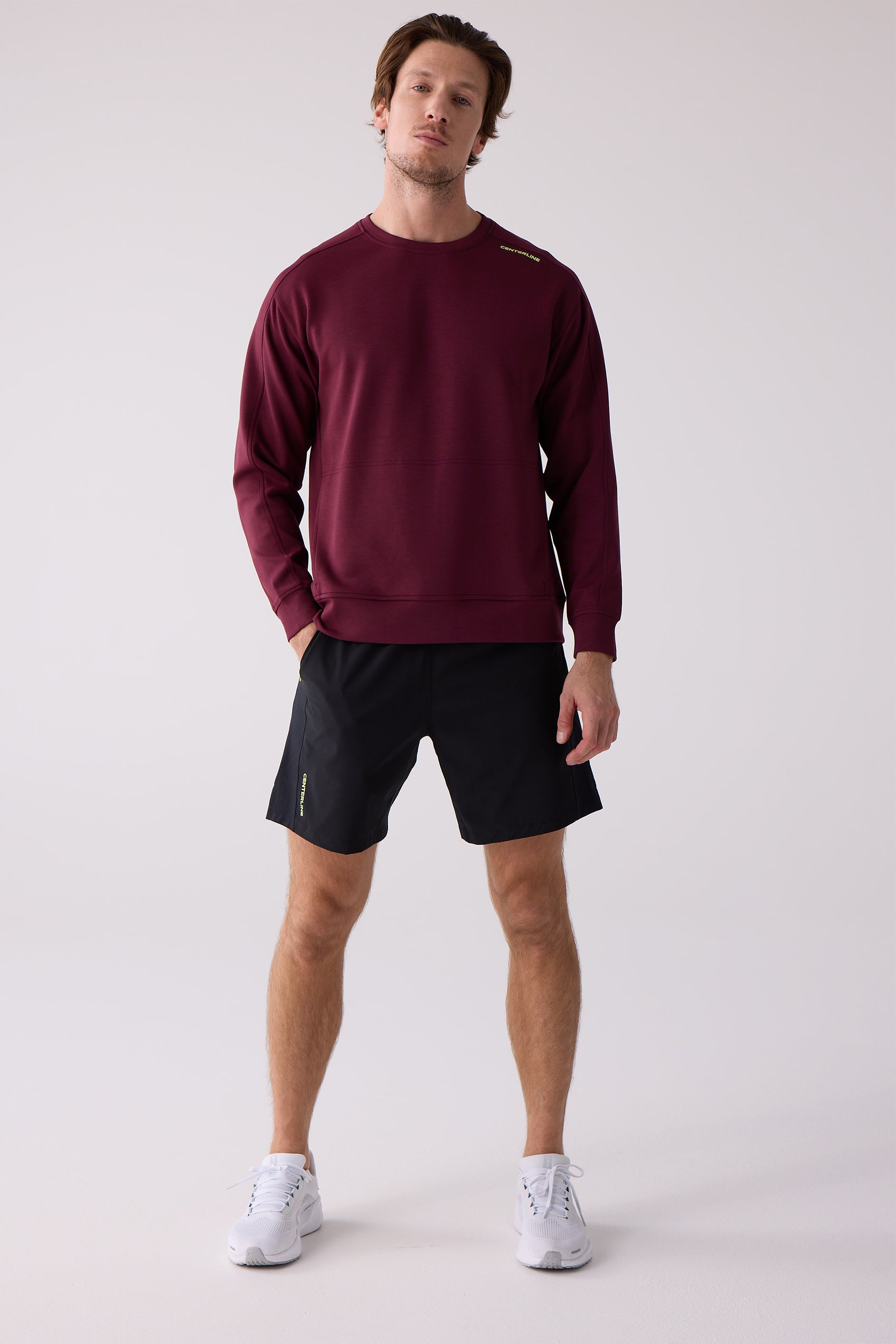 Burgundy crew sweatshirt by Centerline Athletics, featuring yellow 'CENTERLINE' text on the shoulder, worn by a man with black shorts and white sneakers.