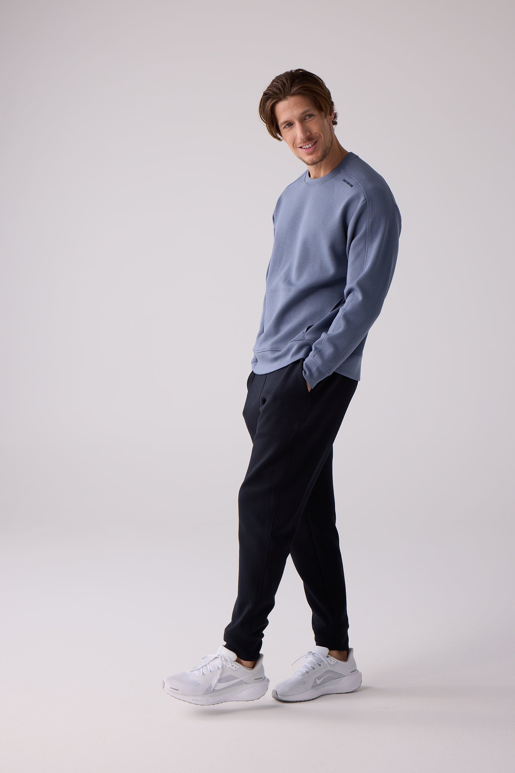 Dusty blue crew sweatshirt by Centerline Athletics, featuring 'CENTERLINE' text on the shoulder, worn by a man in black athletic pants and white sneakers.