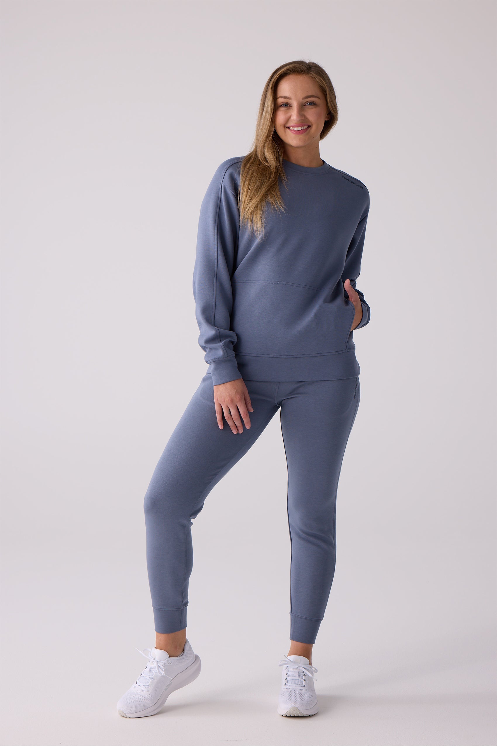 Slate blue women's crew sweatshirt by Centerline Athletics, featuring a front kangaroo pocket and subtle shoulder logo, paired with matching joggers.