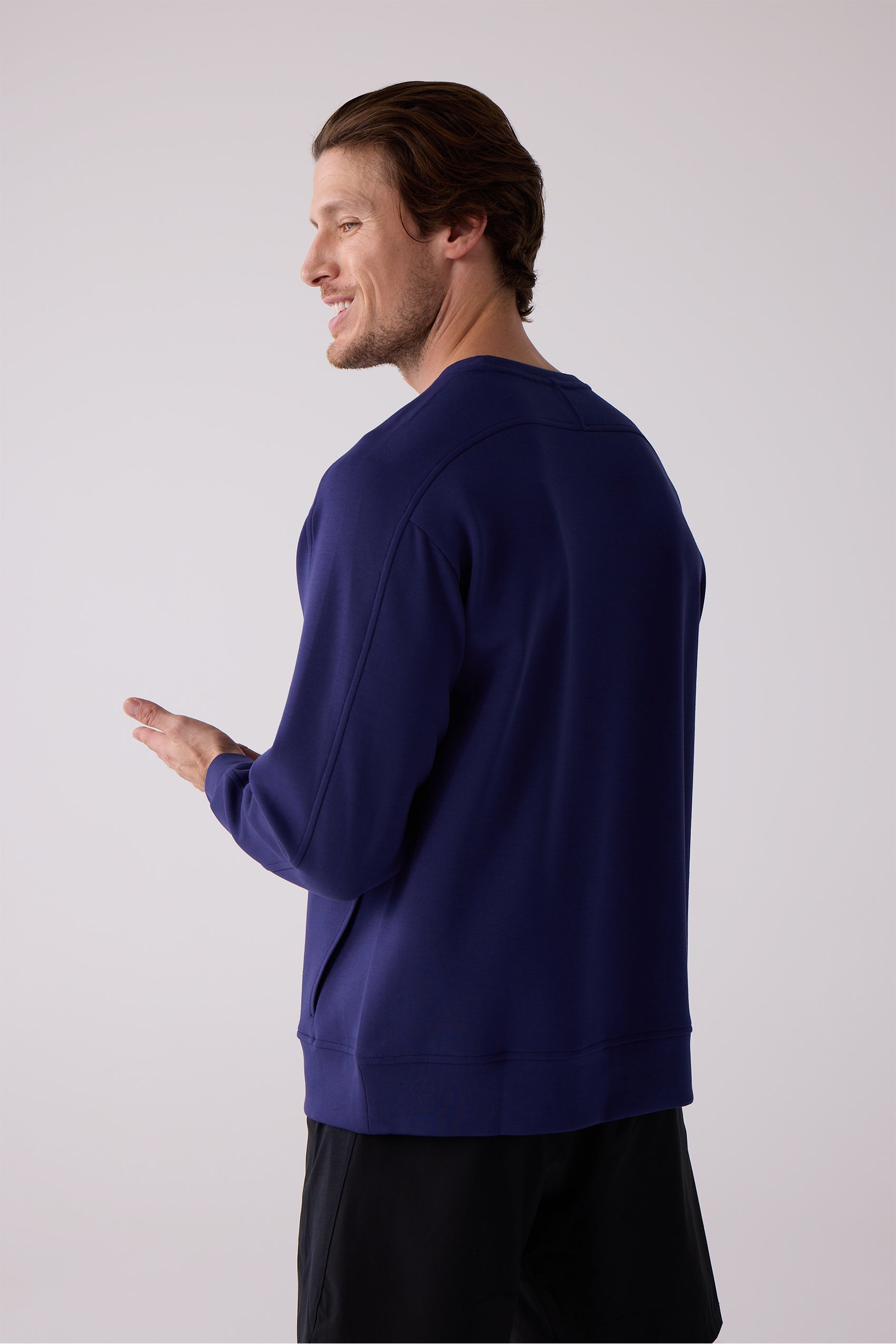 Navy blue men's crew sweatshirt by Centerline Athletics, back-right view on a man smiling and gesturing, with visible stitching and black shorts.
