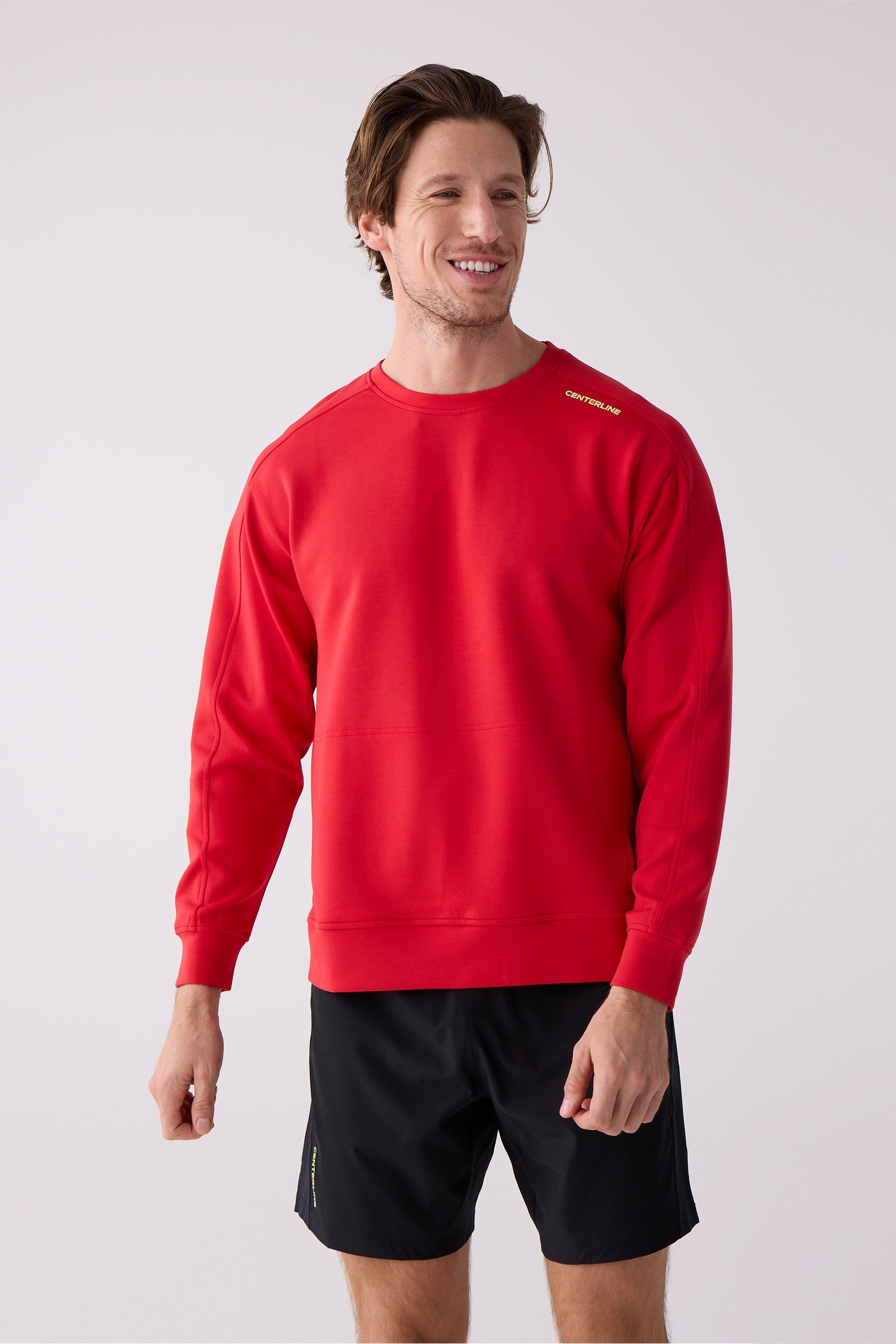 Red men's crew sweatshirt by Centerline Athletics with yellow text logo on the shoulder, worn by a man in black shorts.