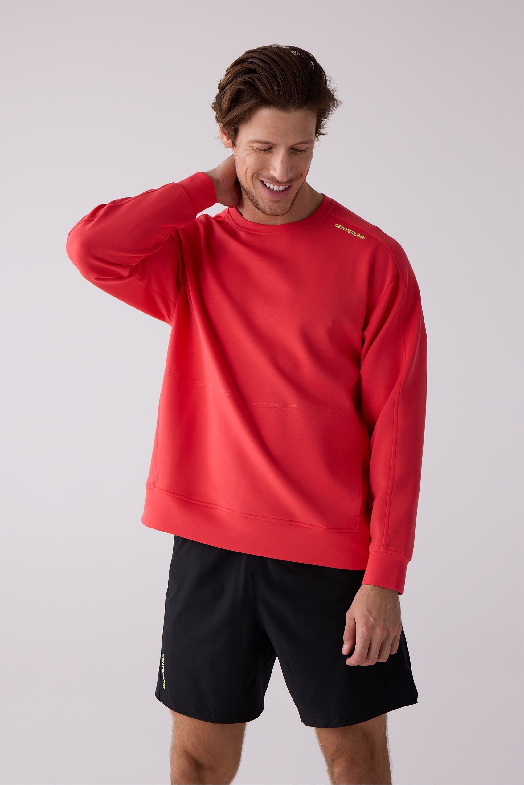 Red crewneck sweatshirt by Centerline Athletics, featuring yellow 'CENTERLINE' text on the shoulder, worn by a man in black shorts.