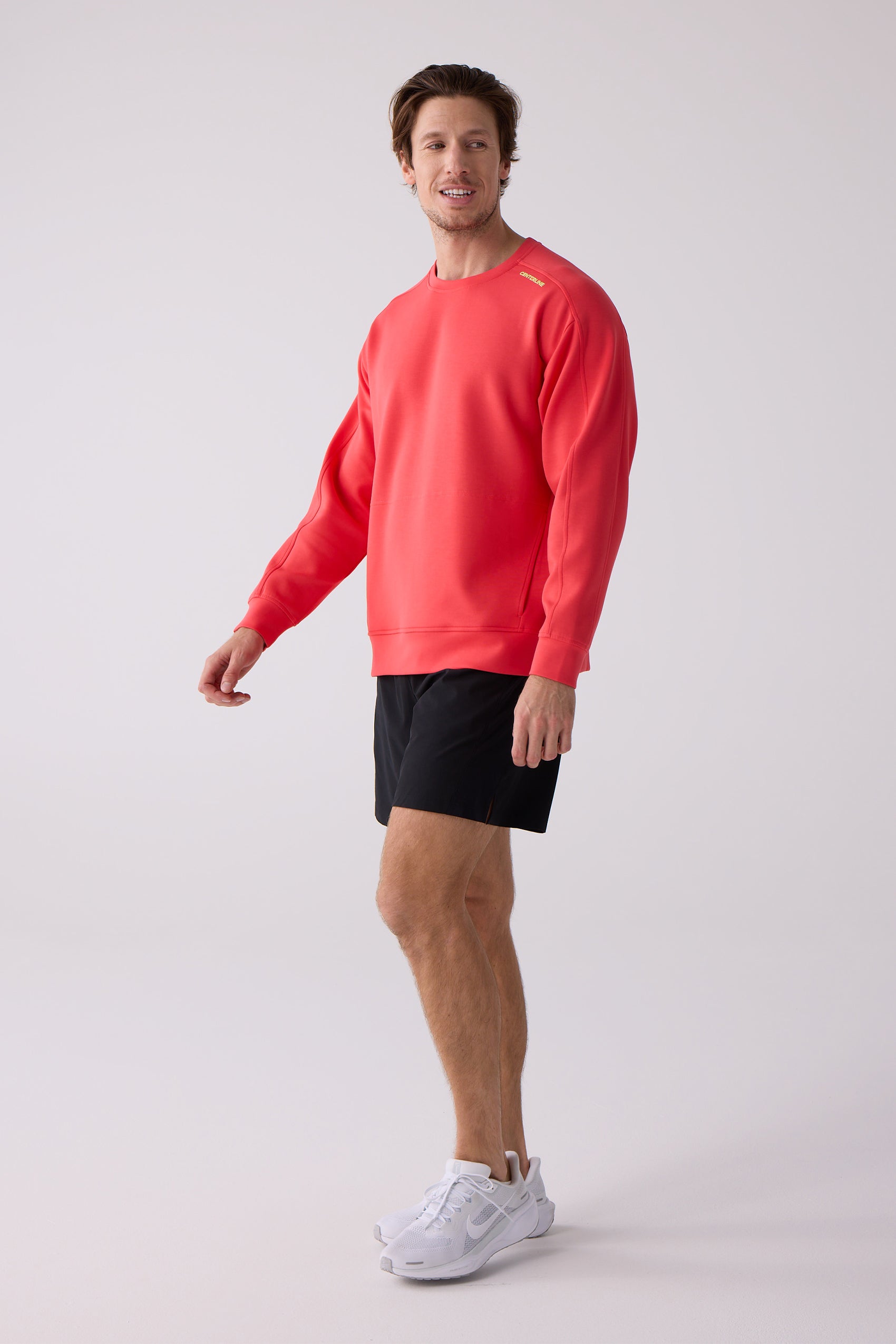 Coral Men's Crew Sweatshirt by Centerline Athletics, featuring "CENTERLINE" on the shoulder, worn by a man with black shorts and white sneakers.