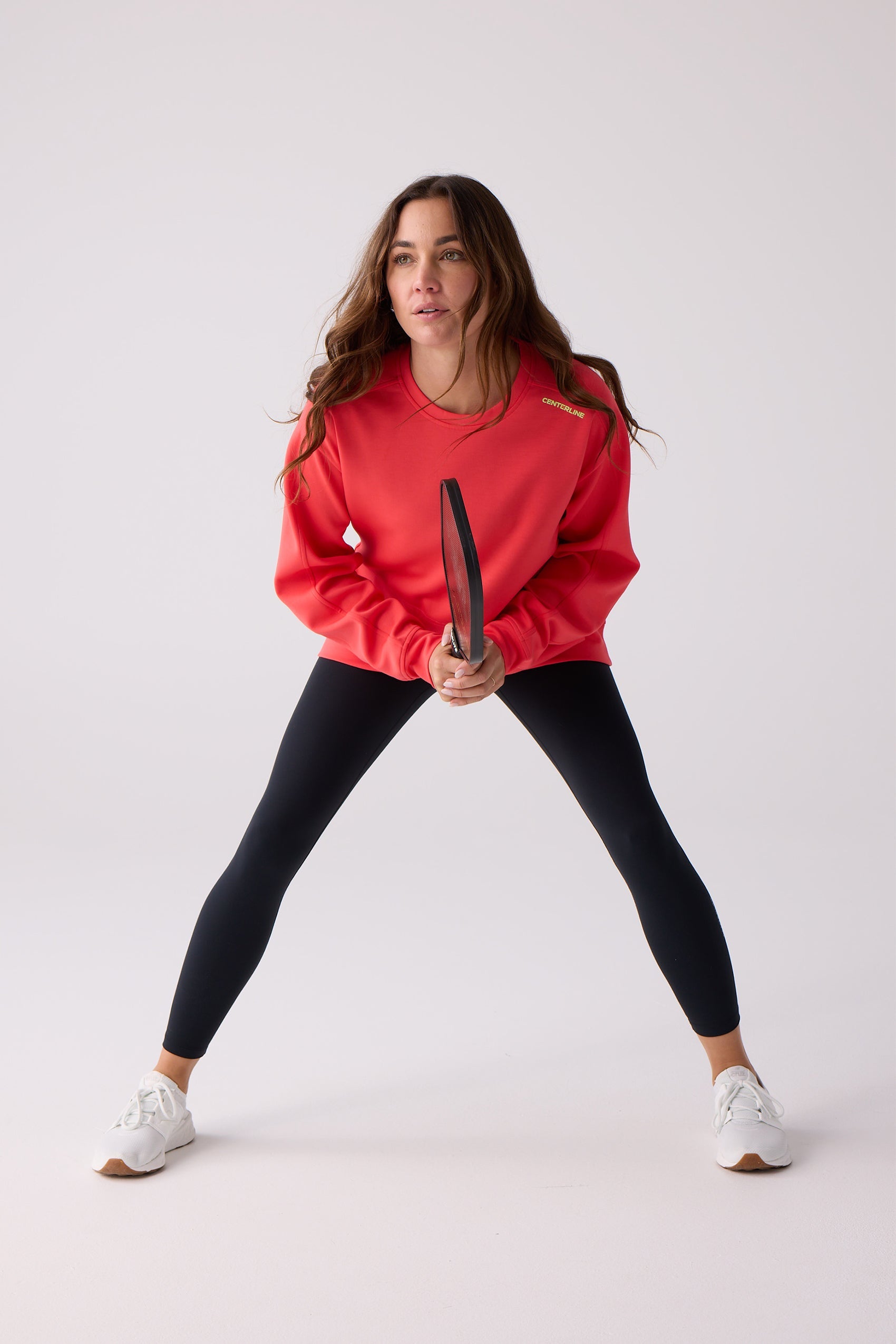 Red crew sweatshirt by Centerline Athletics, featuring 'CENTERLINE' text, worn with black leggings and holding a paddle.
