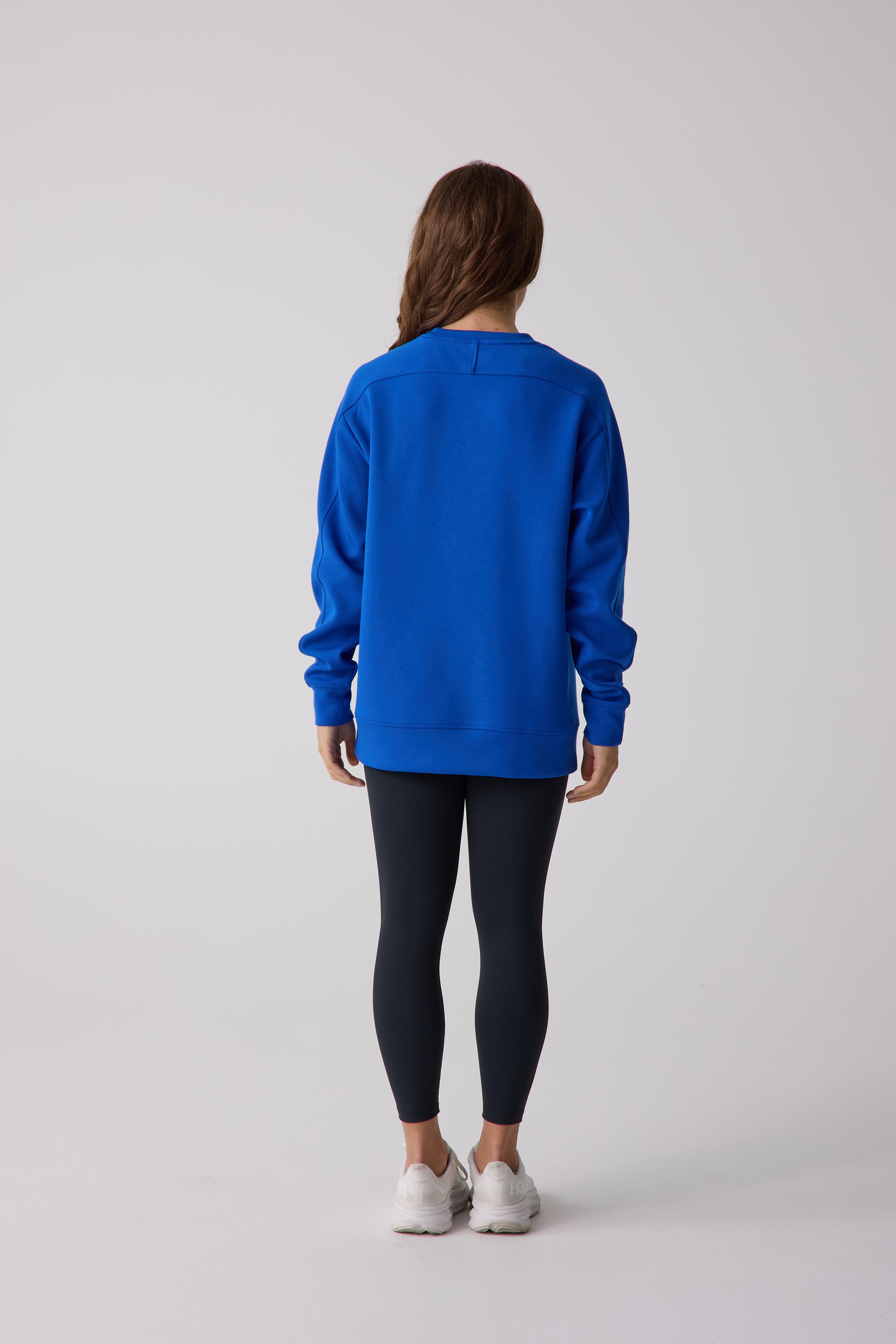 Blue Women's Crew Sweatshirt by Centerline Athletics, shown from the back with black leggings and white sneakers.