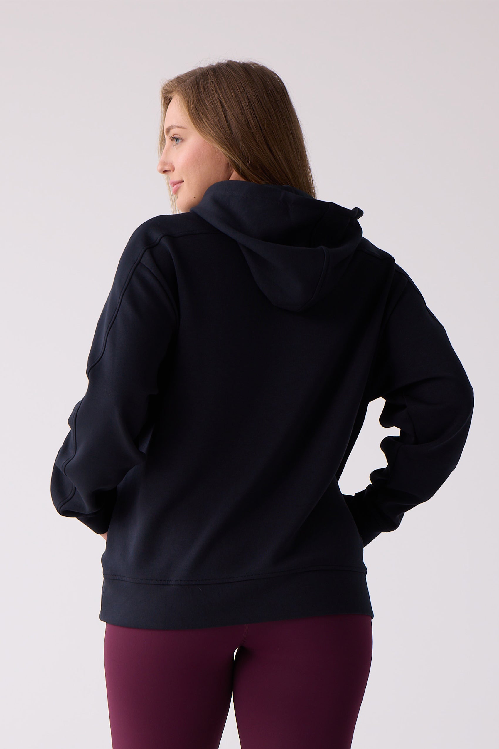 Dark blue women's hooded sweatshirt by Centerline Athletics, shown from the back with visible sleeve seams, worn with burgundy leggings.