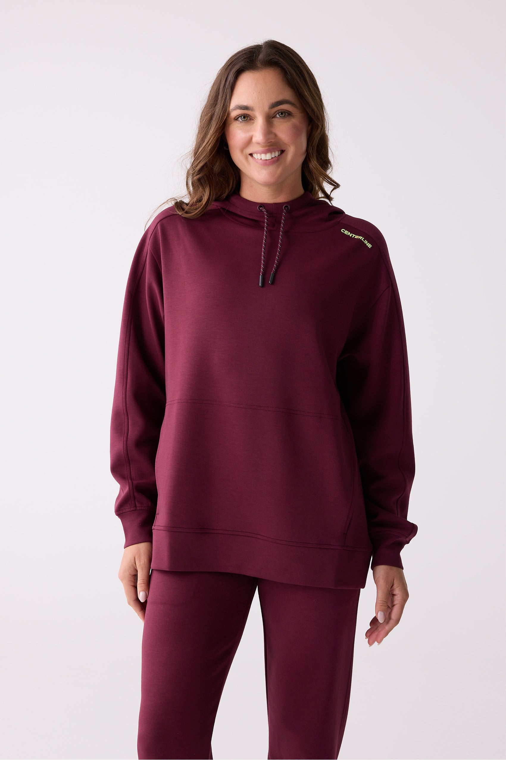 Maroon women's hooded sweatshirt by Centerline Athletics with a drawstring hood, kangaroo pocket, and yellow 'CENTERLINE' shoulder logo, worn with matching maroon pants.