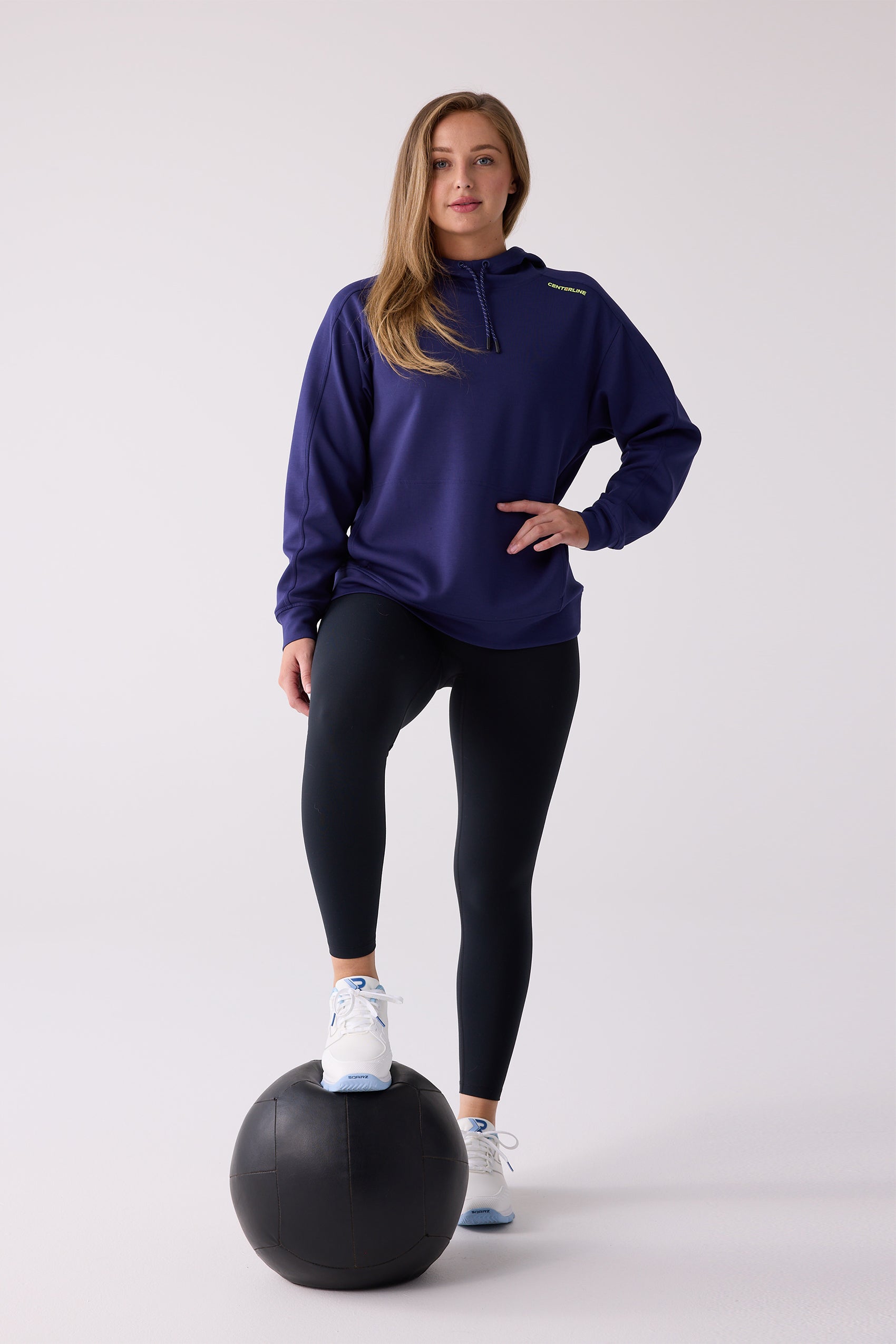 Dark blue women's hooded sweatshirt by Centerline Athletics with yellow 'CENTERLINE' text and speckled drawstring, worn with black leggings.