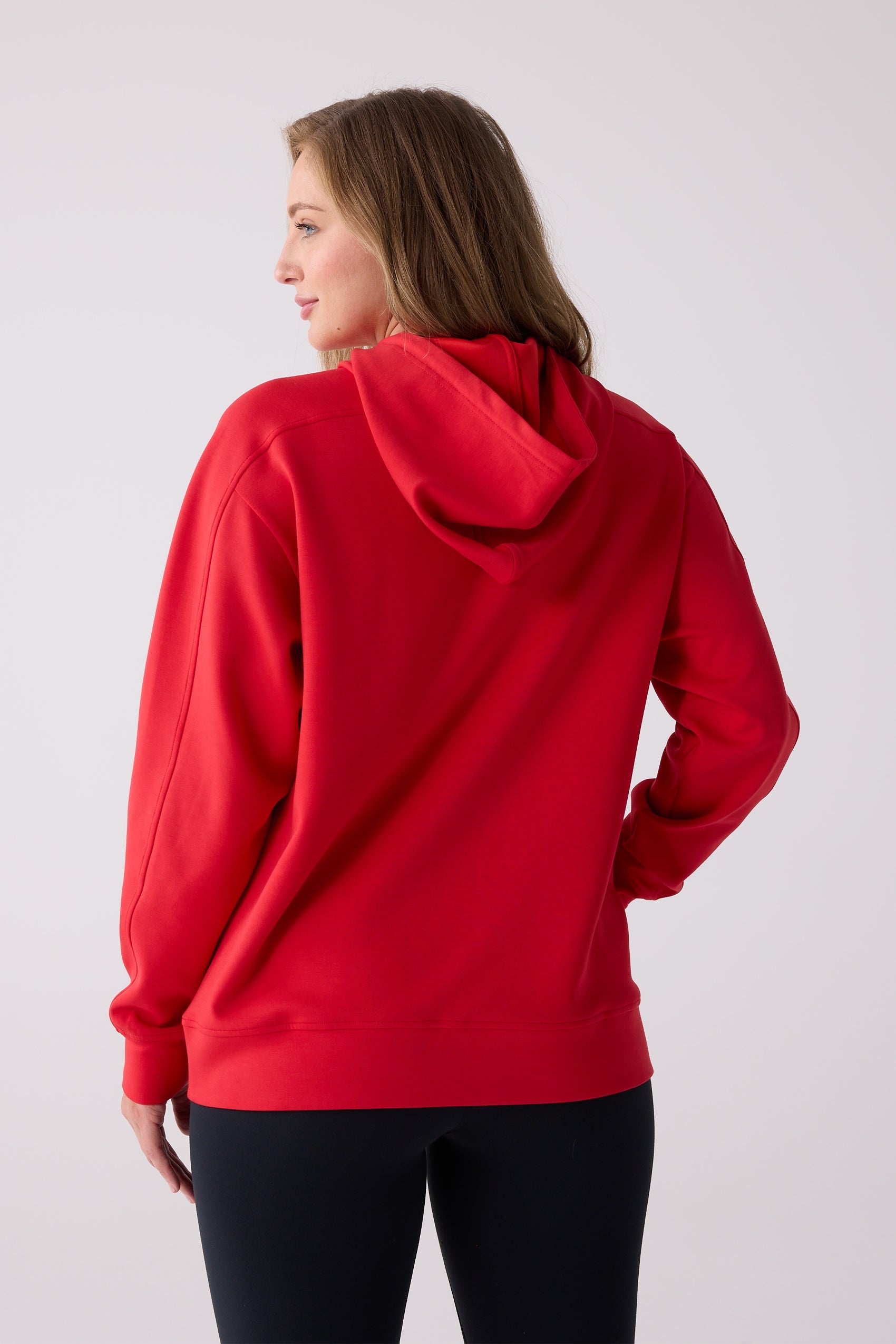 Red hooded sweatshirt by Centerline Athletics, worn by a woman from the back, paired with black leggings.