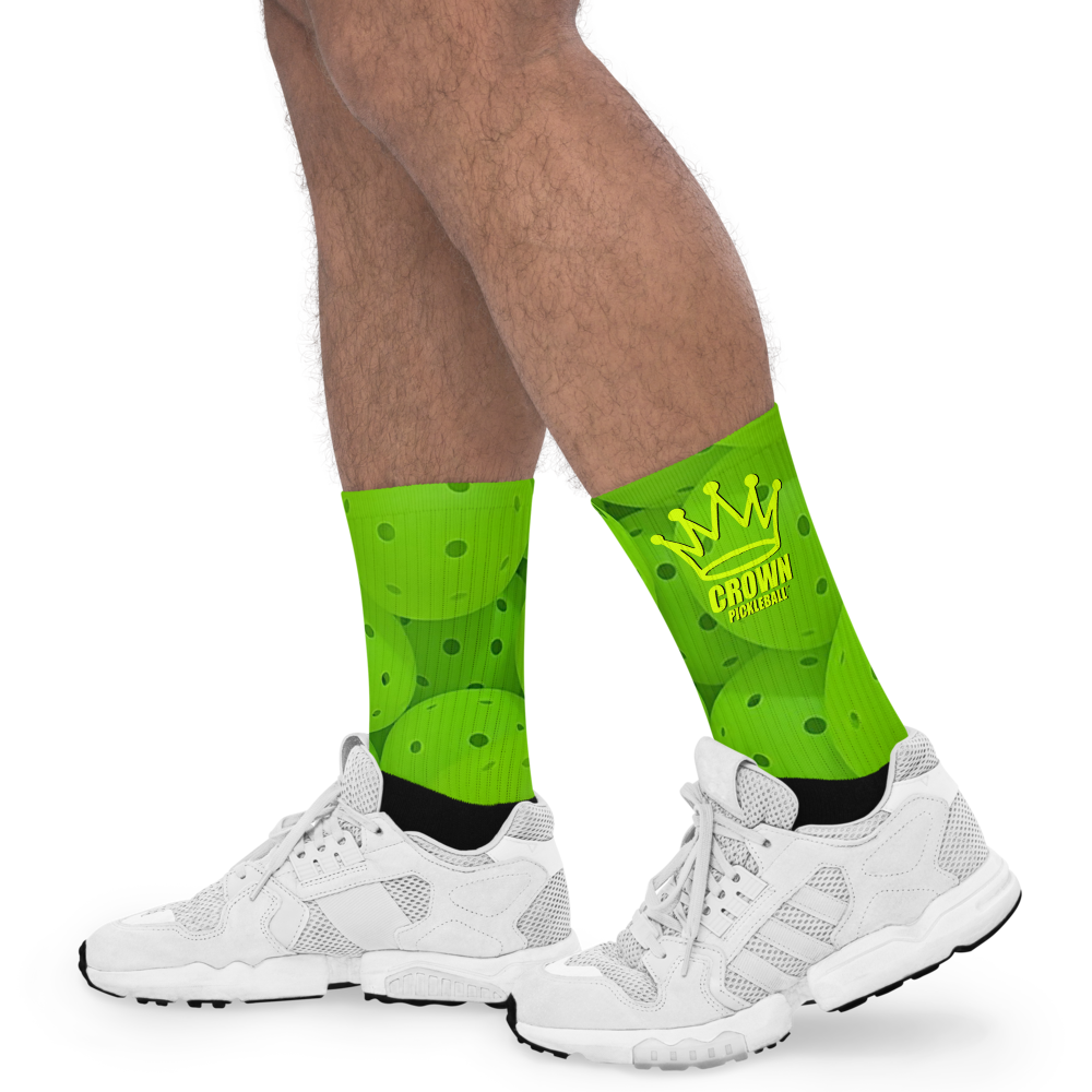 Person wearing green pickleball-themed socks and white athletic shoes.