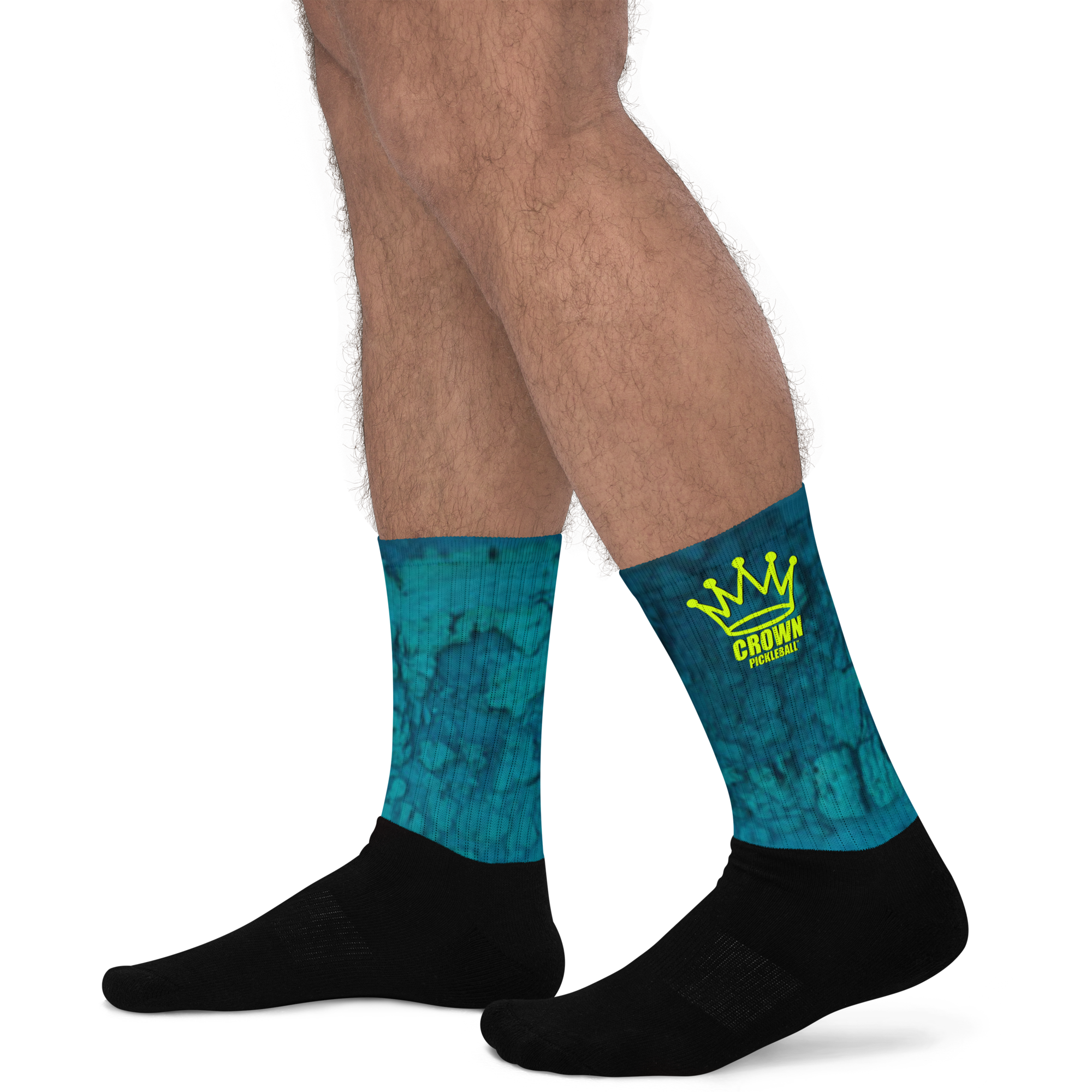 Legs wearing patterned, logoed socks and black ankle socks against a black background.