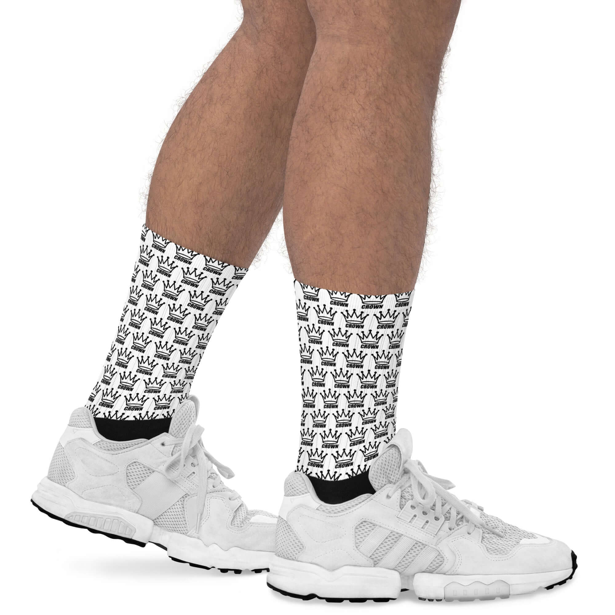 Man wearing white sneakers and white socks with a repeating black crown pattern.