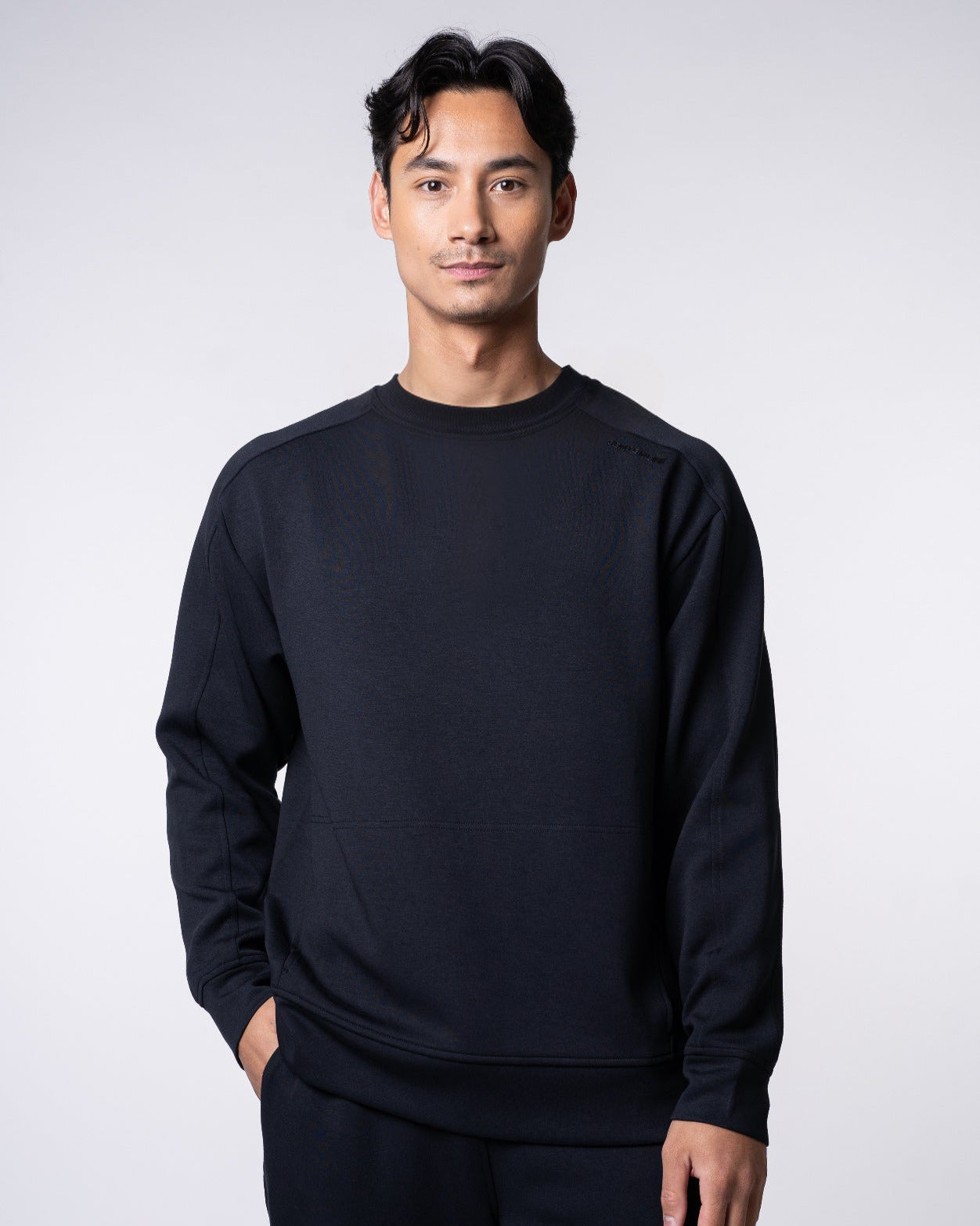 Man in black athletic wear with hand in pocket.
